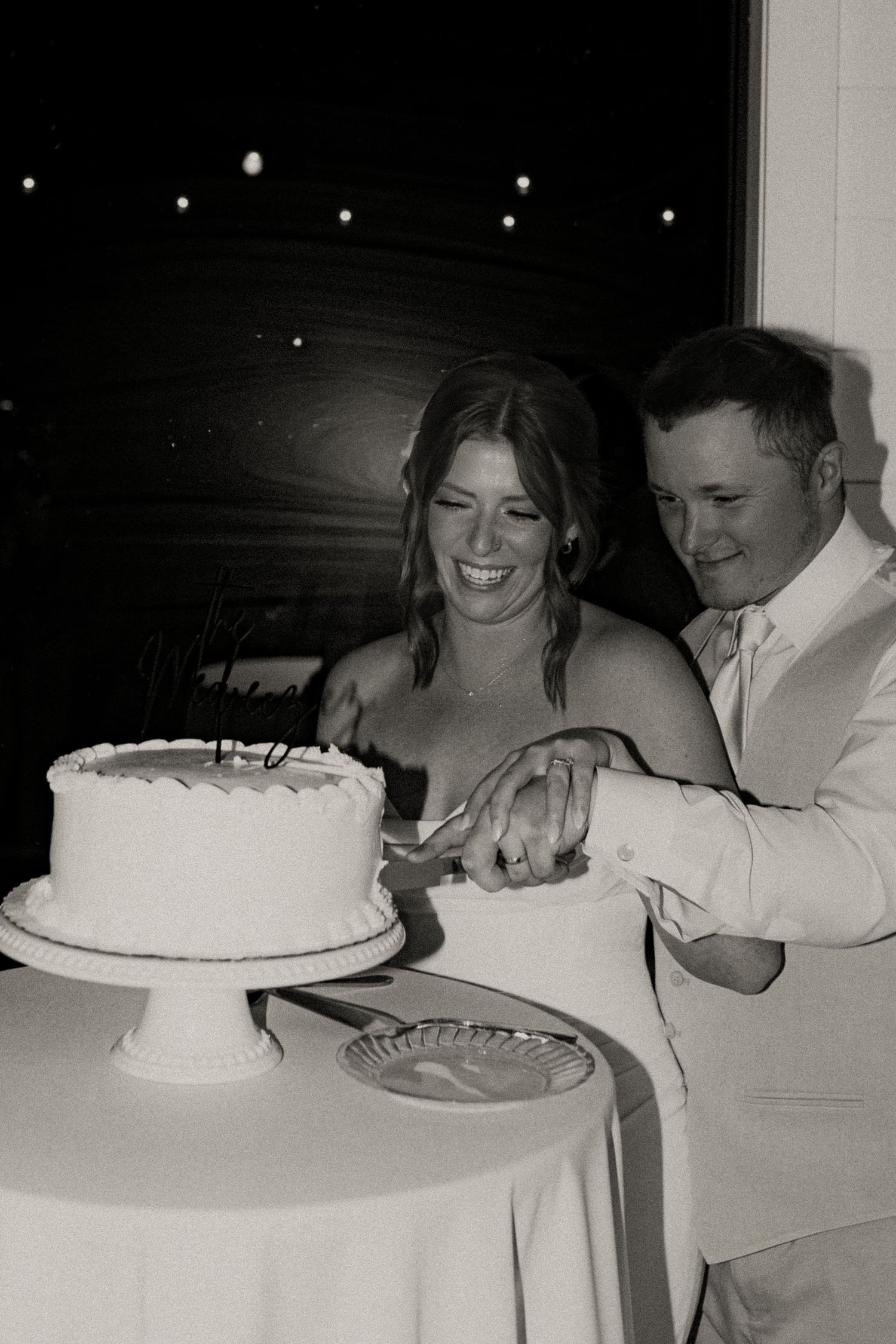 A sequence of black and white photos showing a couple playfully sharing a slice of wedding cake at a reception.