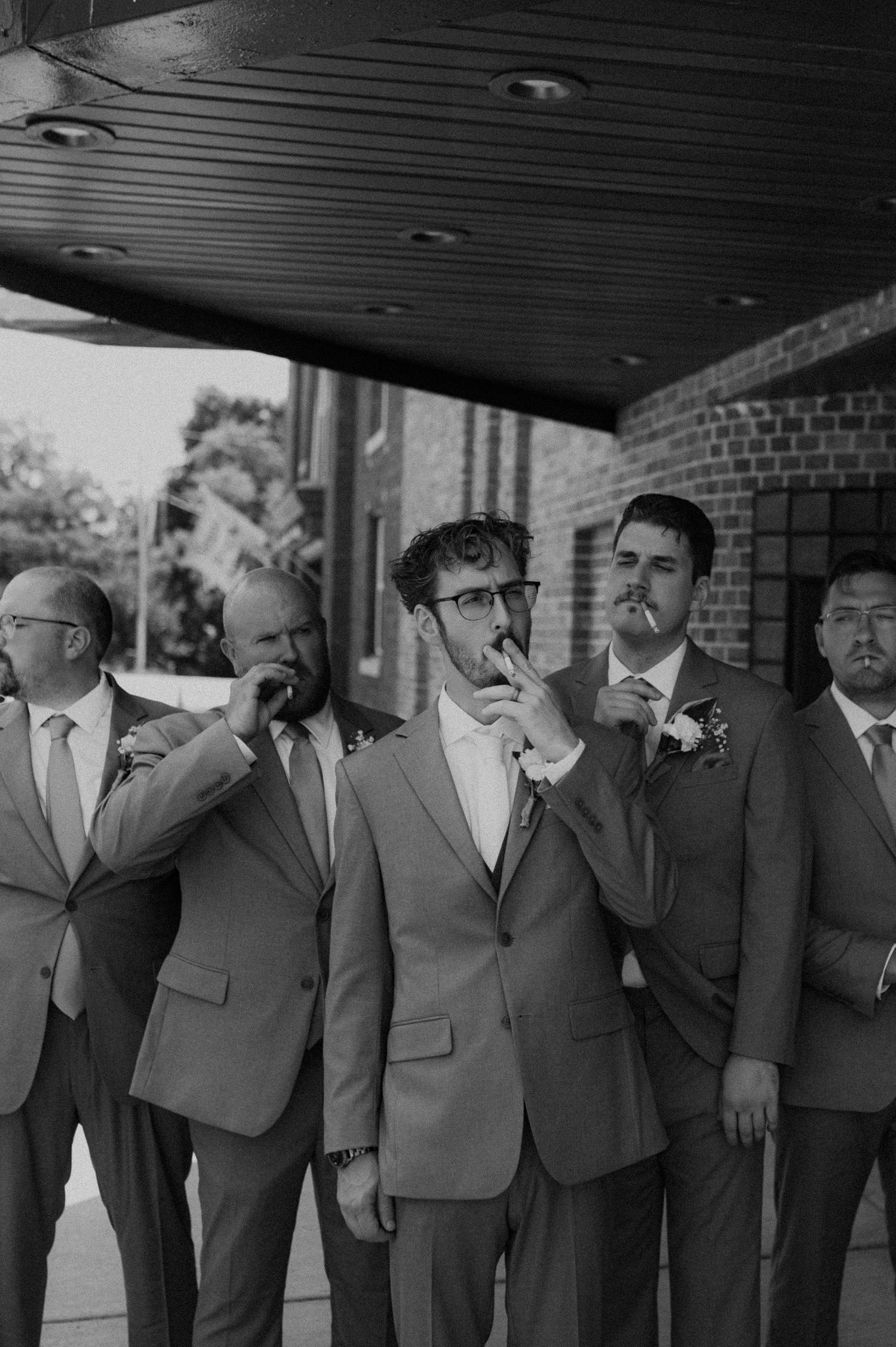 Group of groomsmen in matching suits pretending to cry in a humorous staged photo.