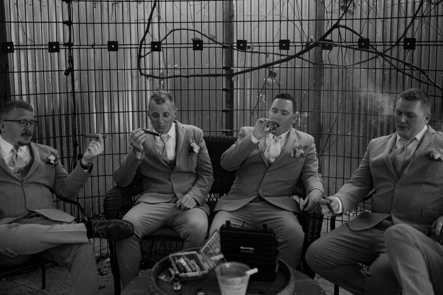 A group of men in suits sit together in conversation at an outdoor gathering in this vintage black and white photograph.