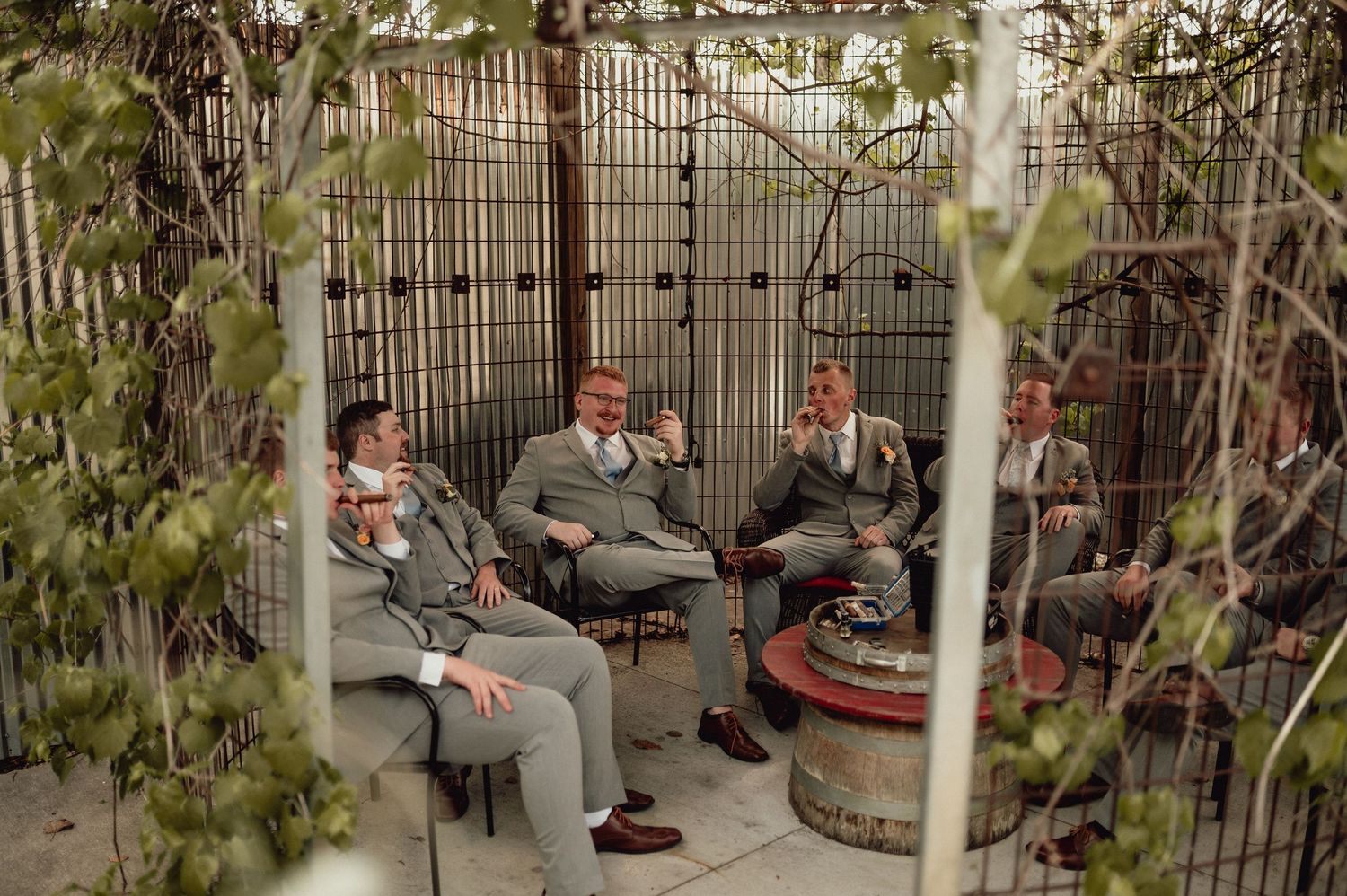 Students sitting on a curved stone bench in an outdoor courtyard area surrounded by plants and fencing.