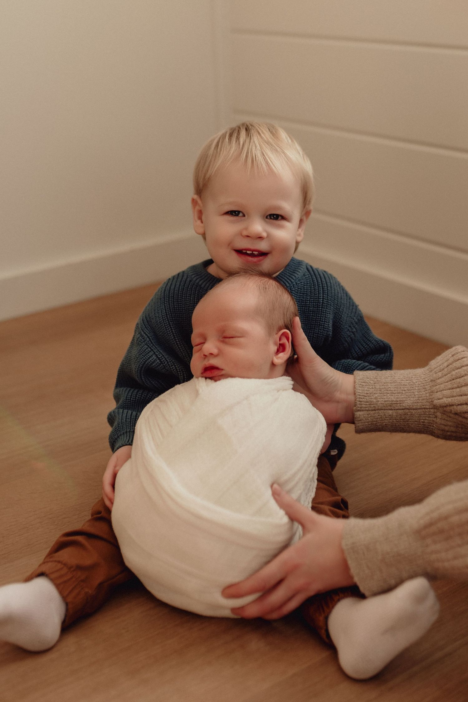 A series of photos showing a baby being swaddled in white fabric on a brown surface.