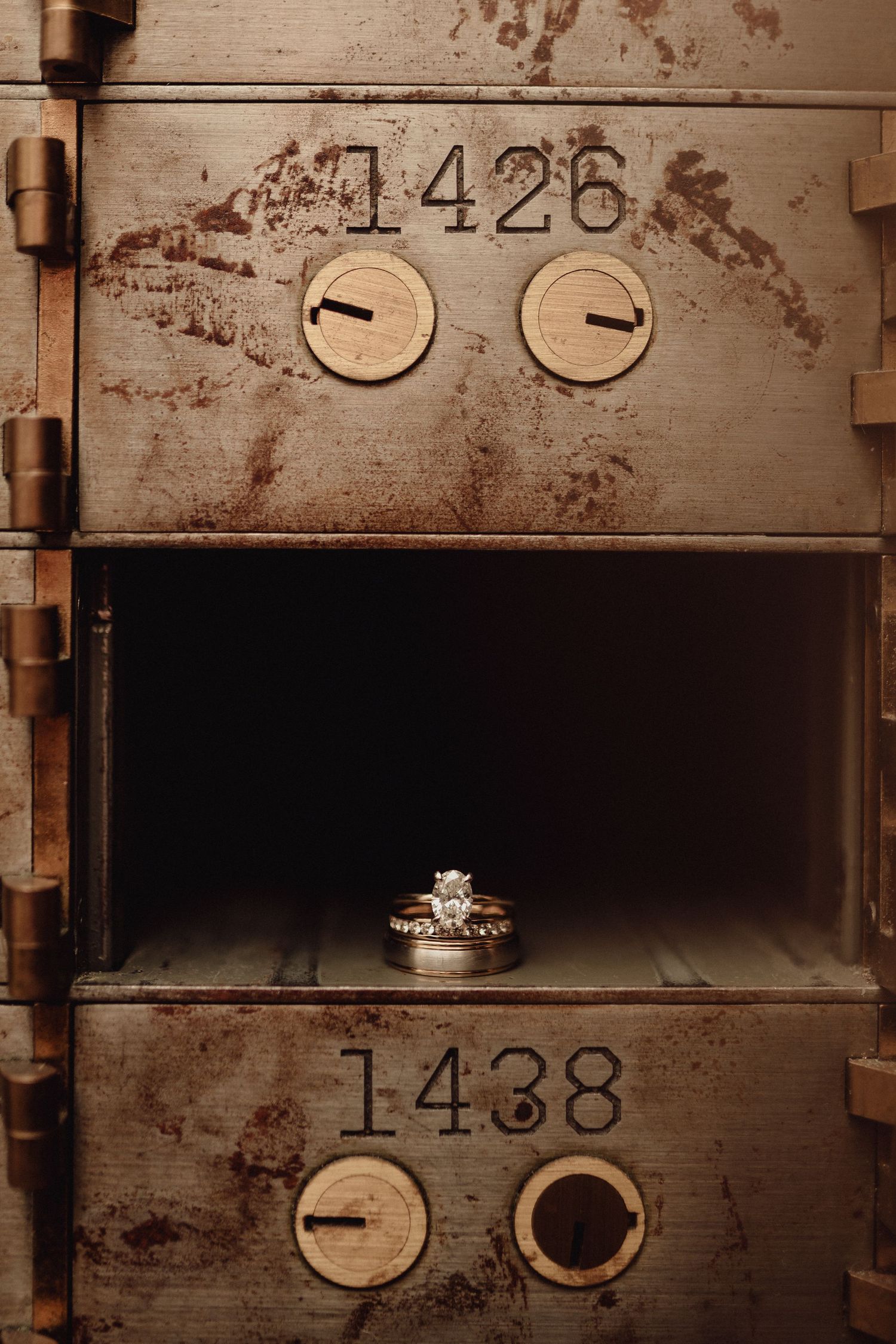 Vintage bank safety deposit boxes with numbered brass plates and keyholes on weathered metal surface.