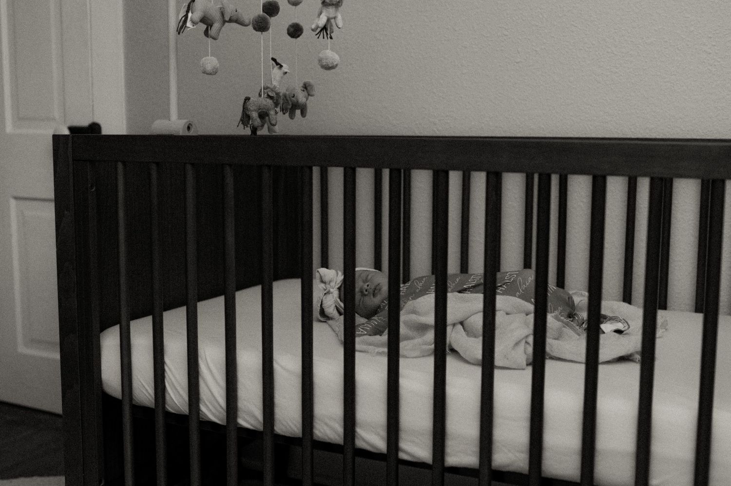 Black and white nursery photos showing a crib and gentle lighting.