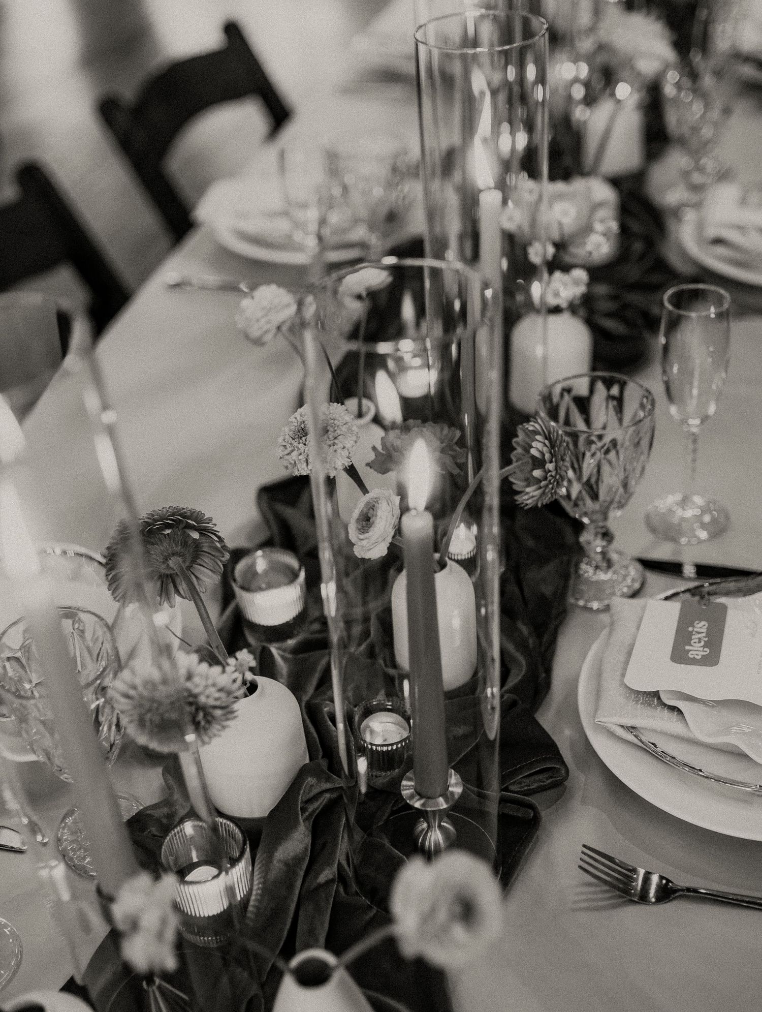 Elegant table setting with candles and floral centerpieces at a wedding reception.