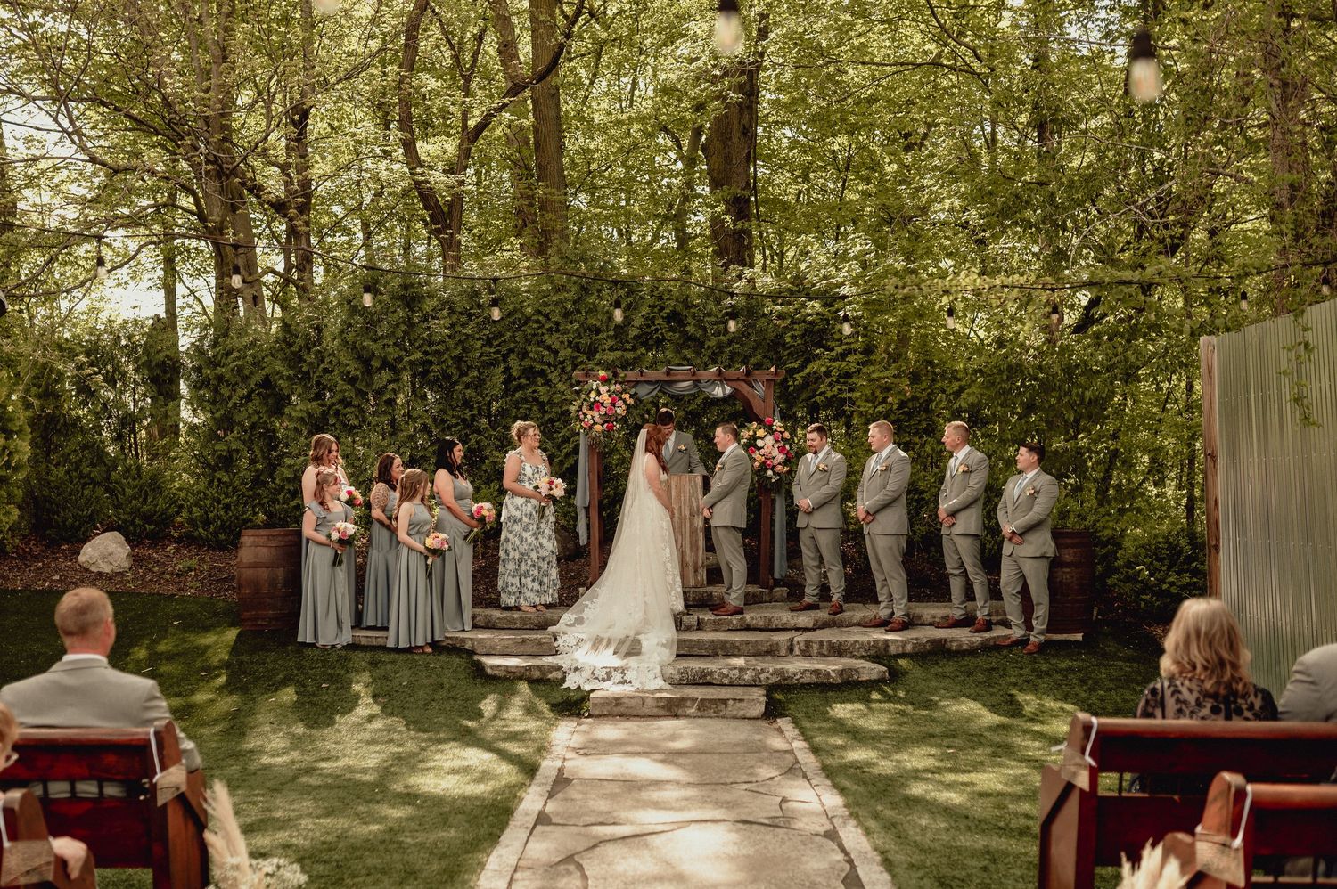 Wedding ceremony taking place in a serene outdoor garden setting with guests seated in white chairs.
