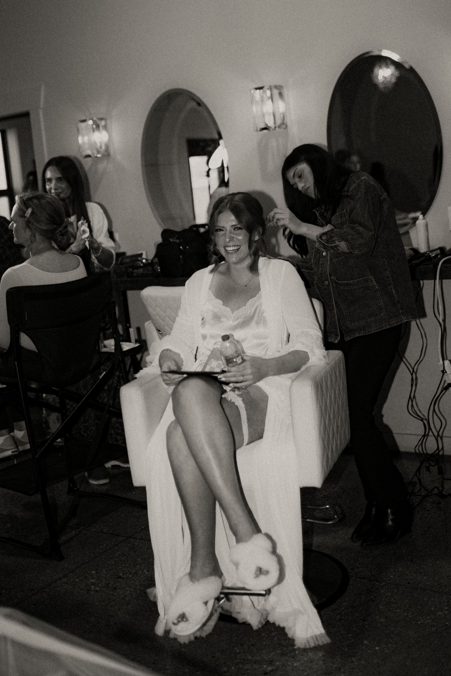 Black and white photo series showing a person seated in a white chair at what appears to be a salon or styling session.