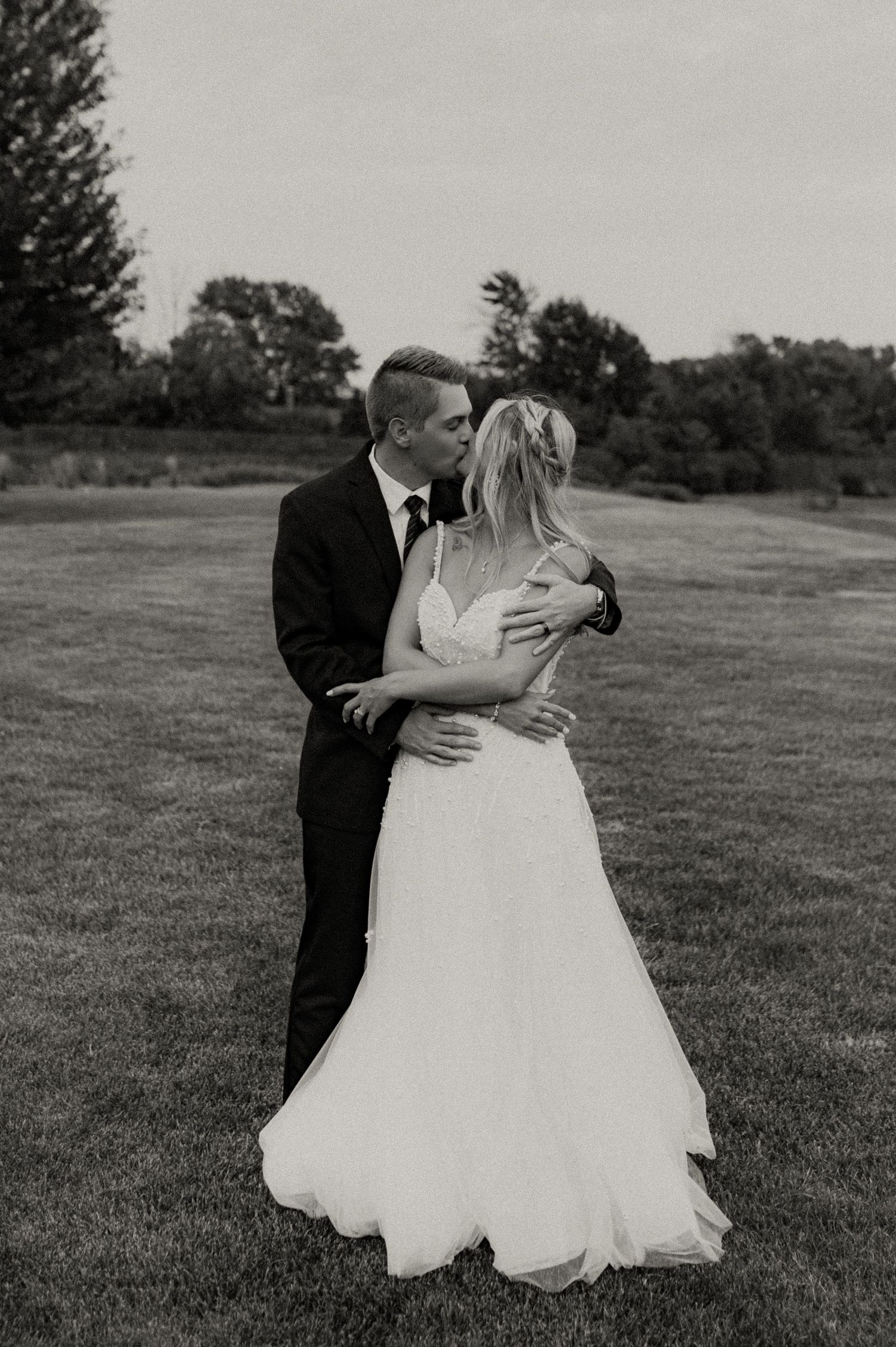 Black and white wedding photos showing romantic moments in an outdoor field setting.