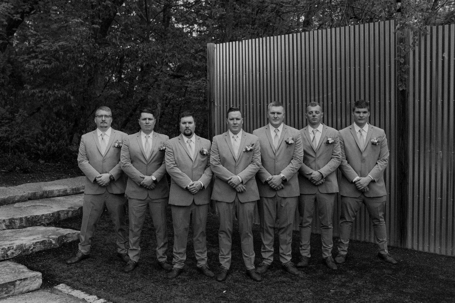 A black and white photo collage showing a group of people sitting on a bench in similar formal attire outdoors.