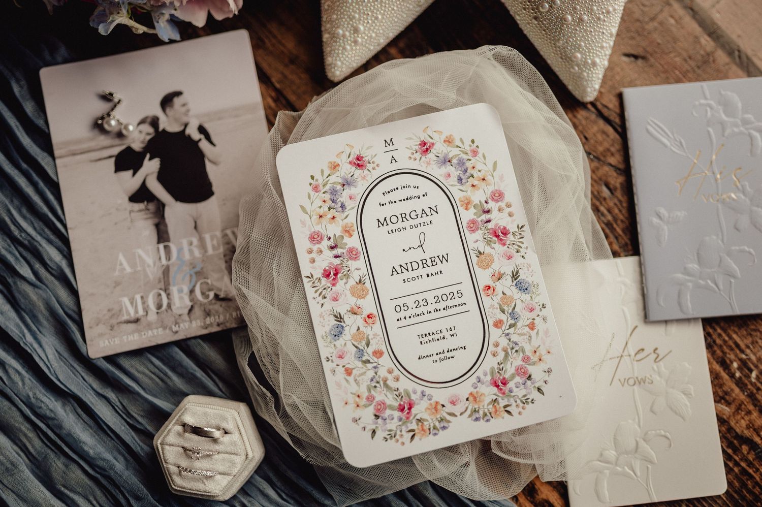 Elegant wedding stationery with floral designs and calligraphy displayed in a collection on a wooden surface.