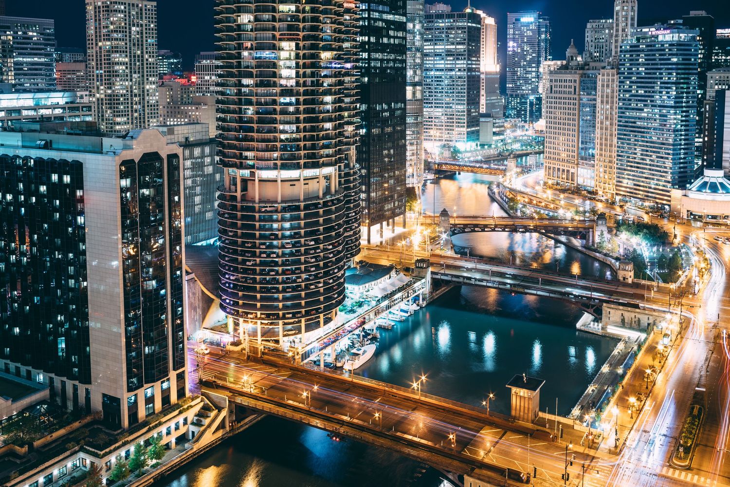 Aerial view of Chicago River at night with illuminated buildings and bridges.