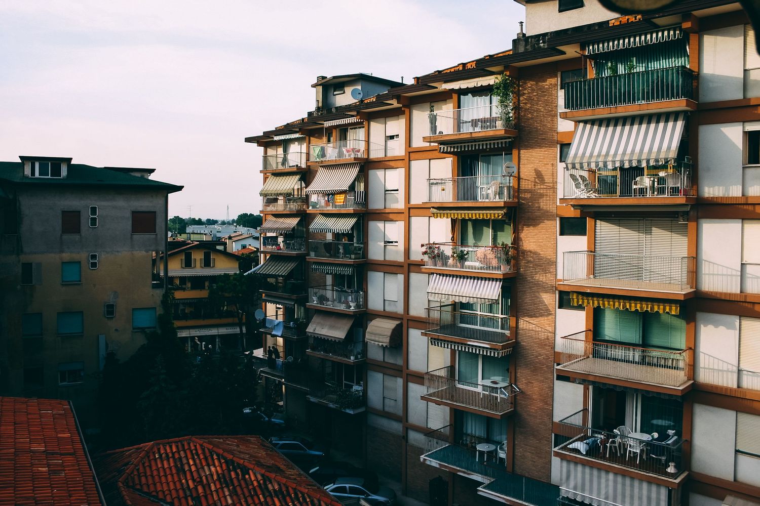 Urban residential buildings with balconies and green accents seen from a distance.
