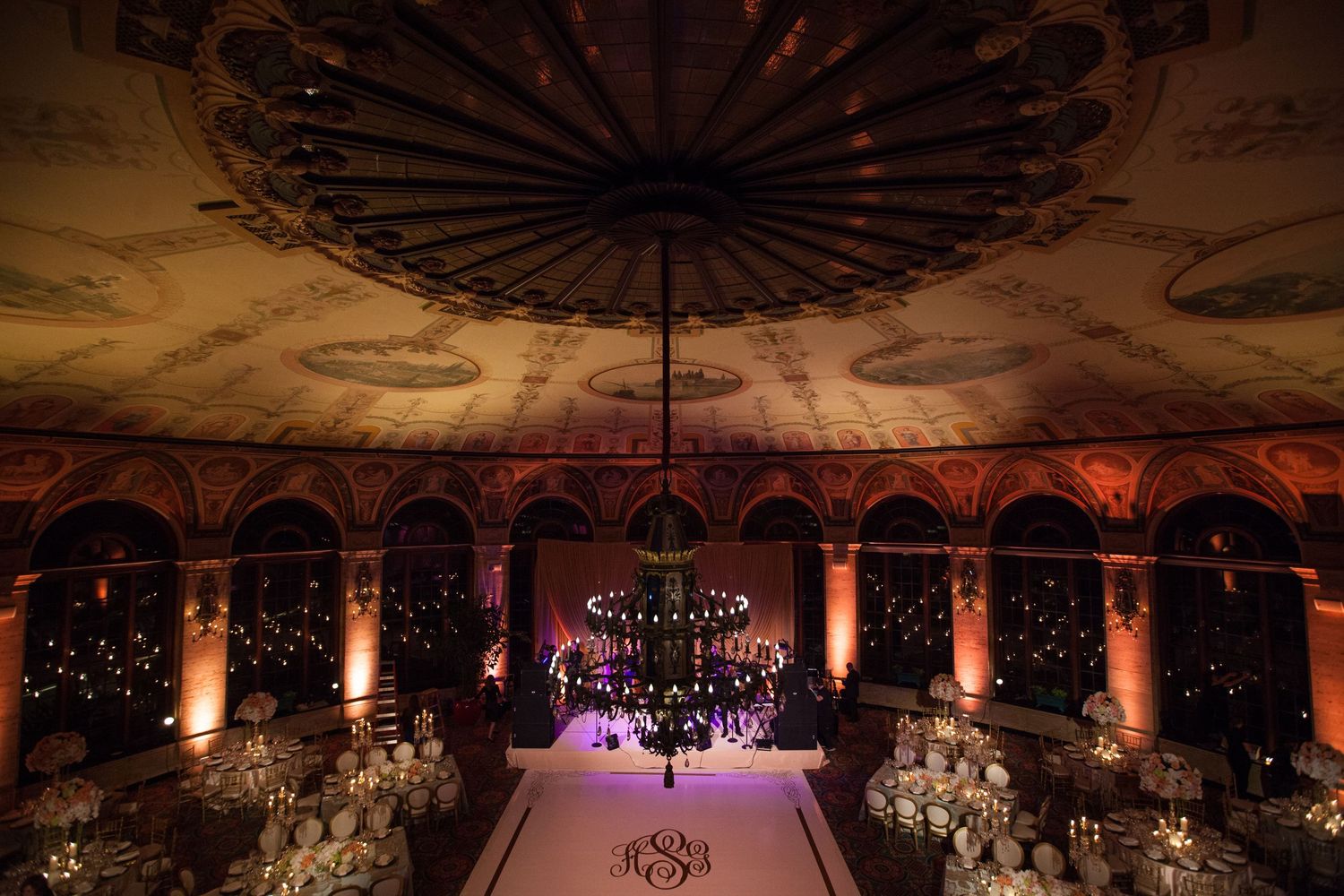 An elegant ballroom with crystal chandeliers and gold accents is illuminated in warm lighting for a special event.
