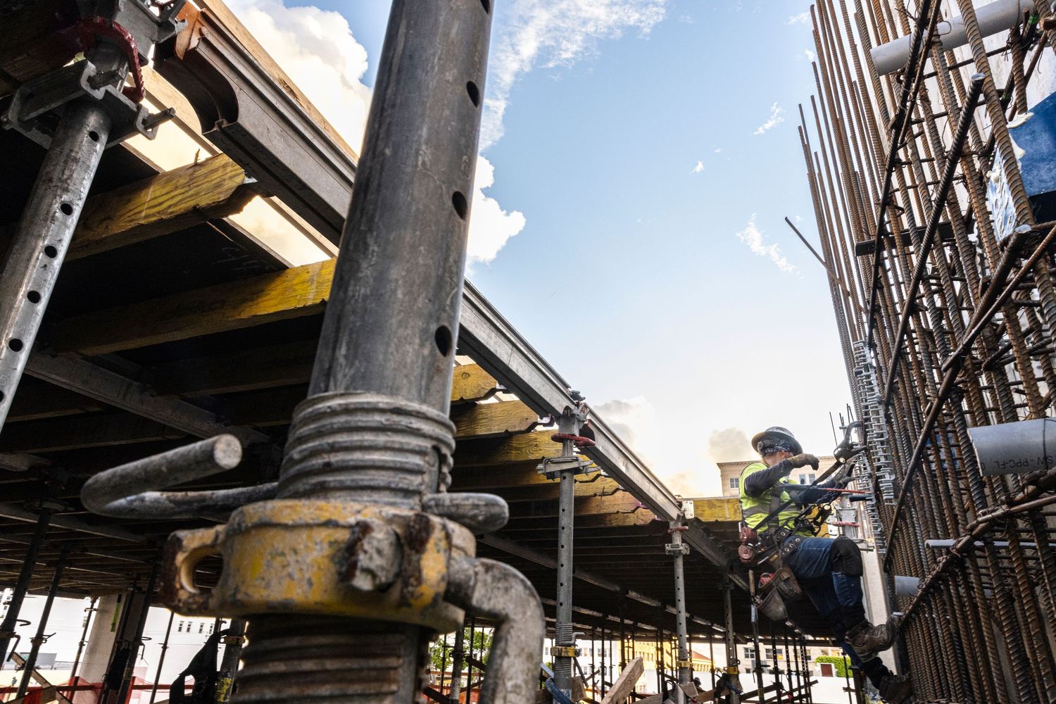 Industrial steel beams and metal structures form architectural details against a bright blue sky.