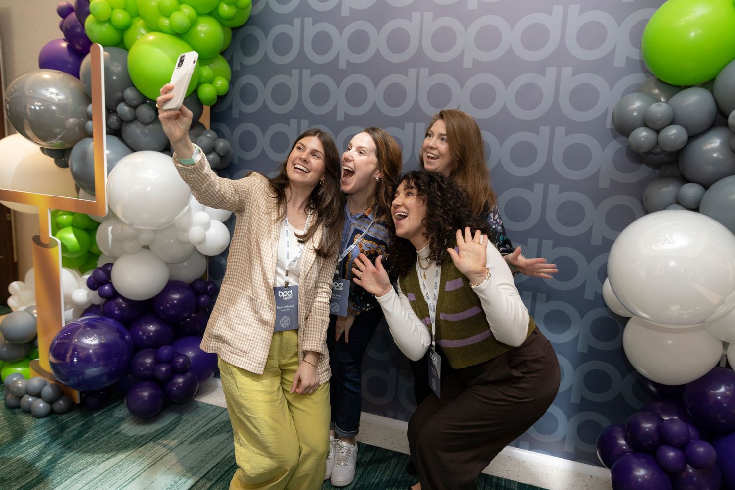 Corporate event space decorated with green, purple and white balloon arrangements.
