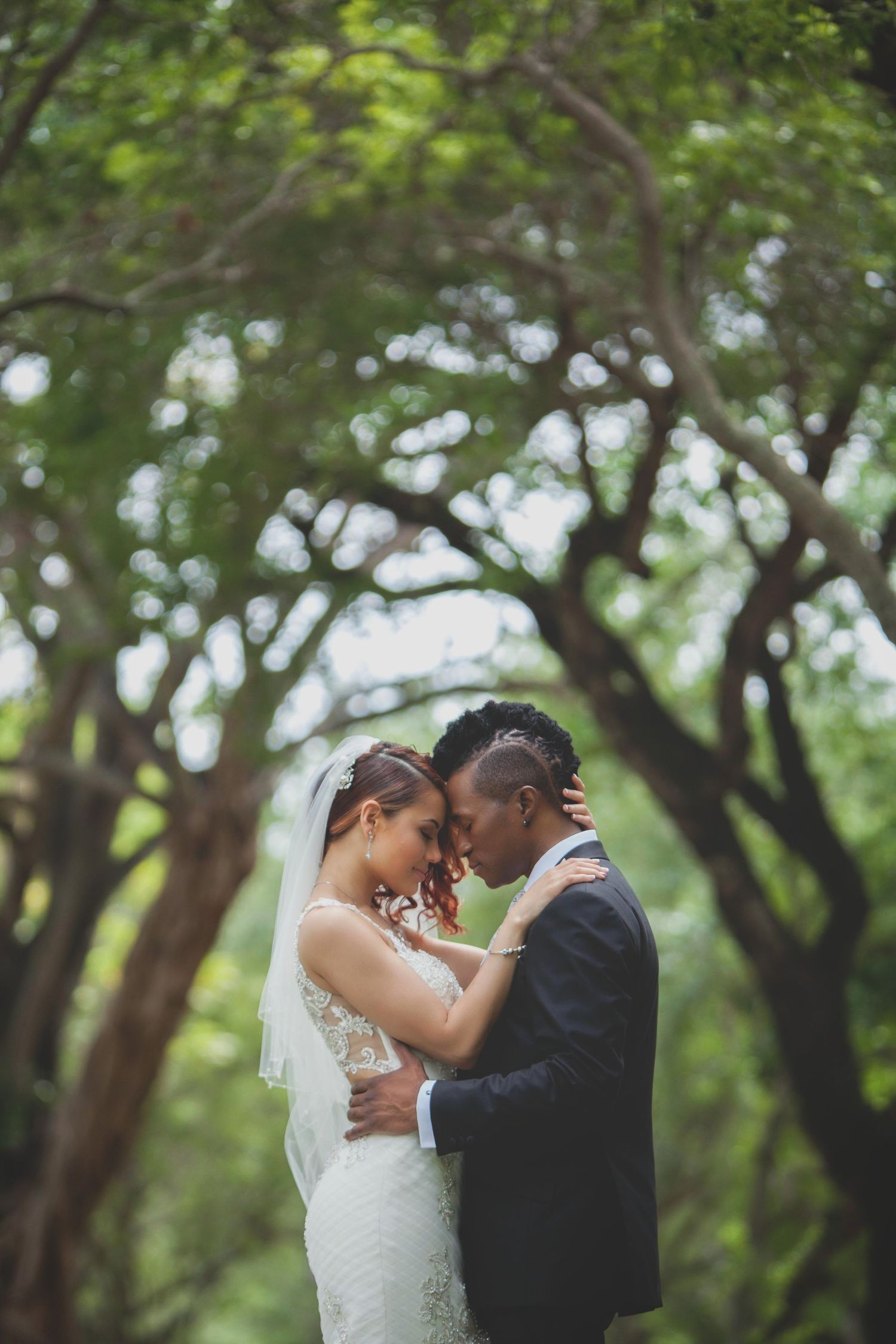 Intimate wedding couple portrait under a canopy of green trees.