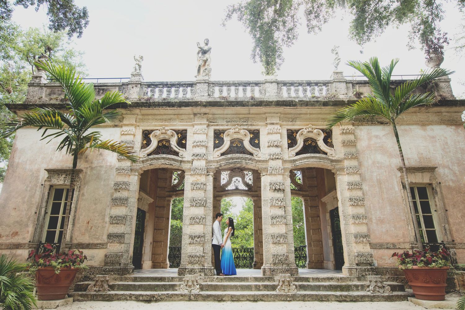 Historic colonial architecture facade with ornate stone carvings and palm trees.