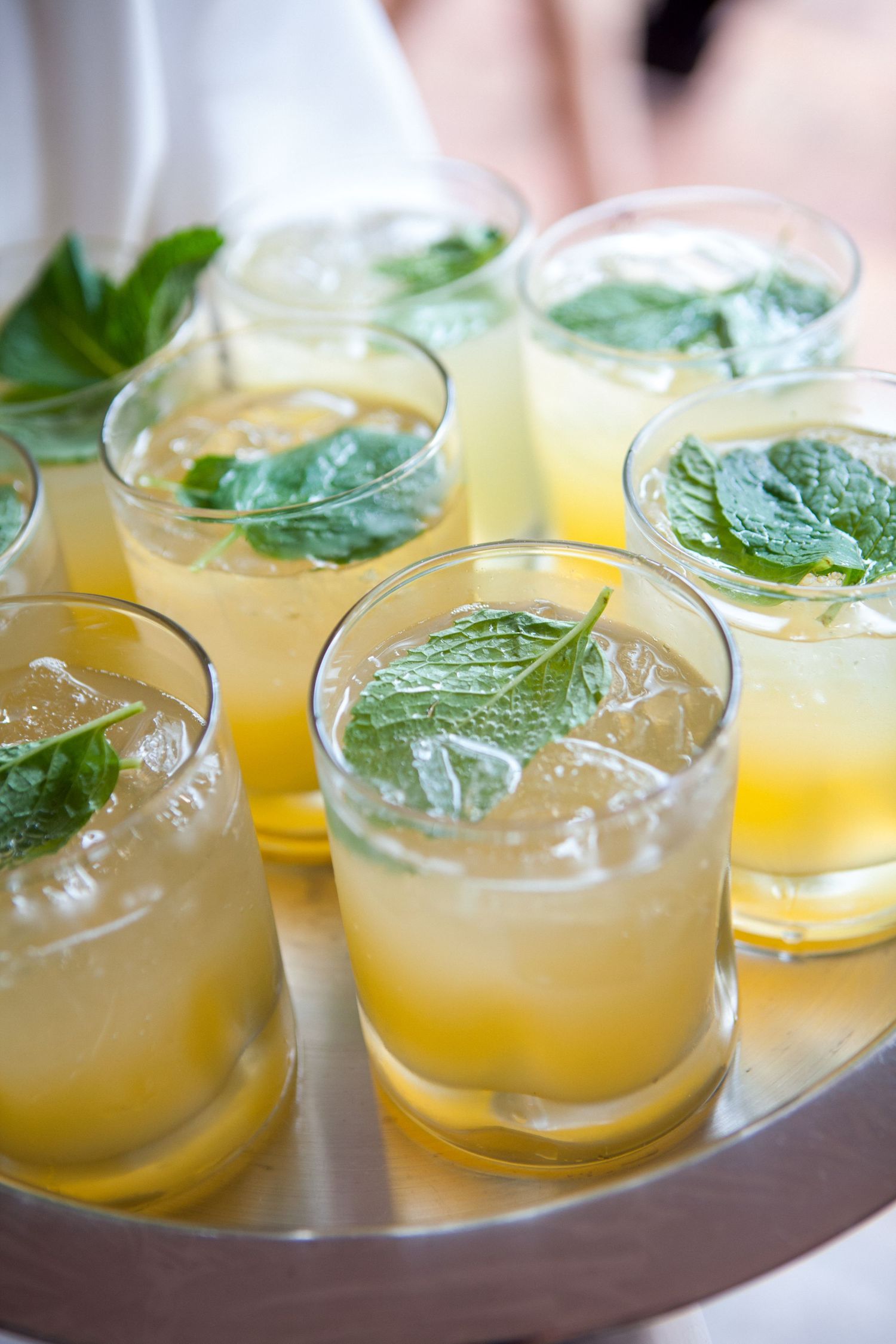 Row of refreshing citrus cocktails garnished with fresh mint leaves.