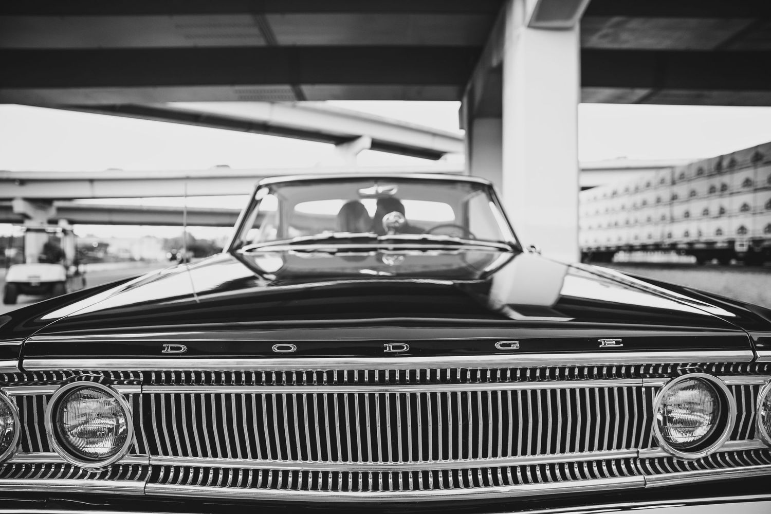 Close-up black and white photography of vintage chrome car trim and grilles showing reflective metallic details.