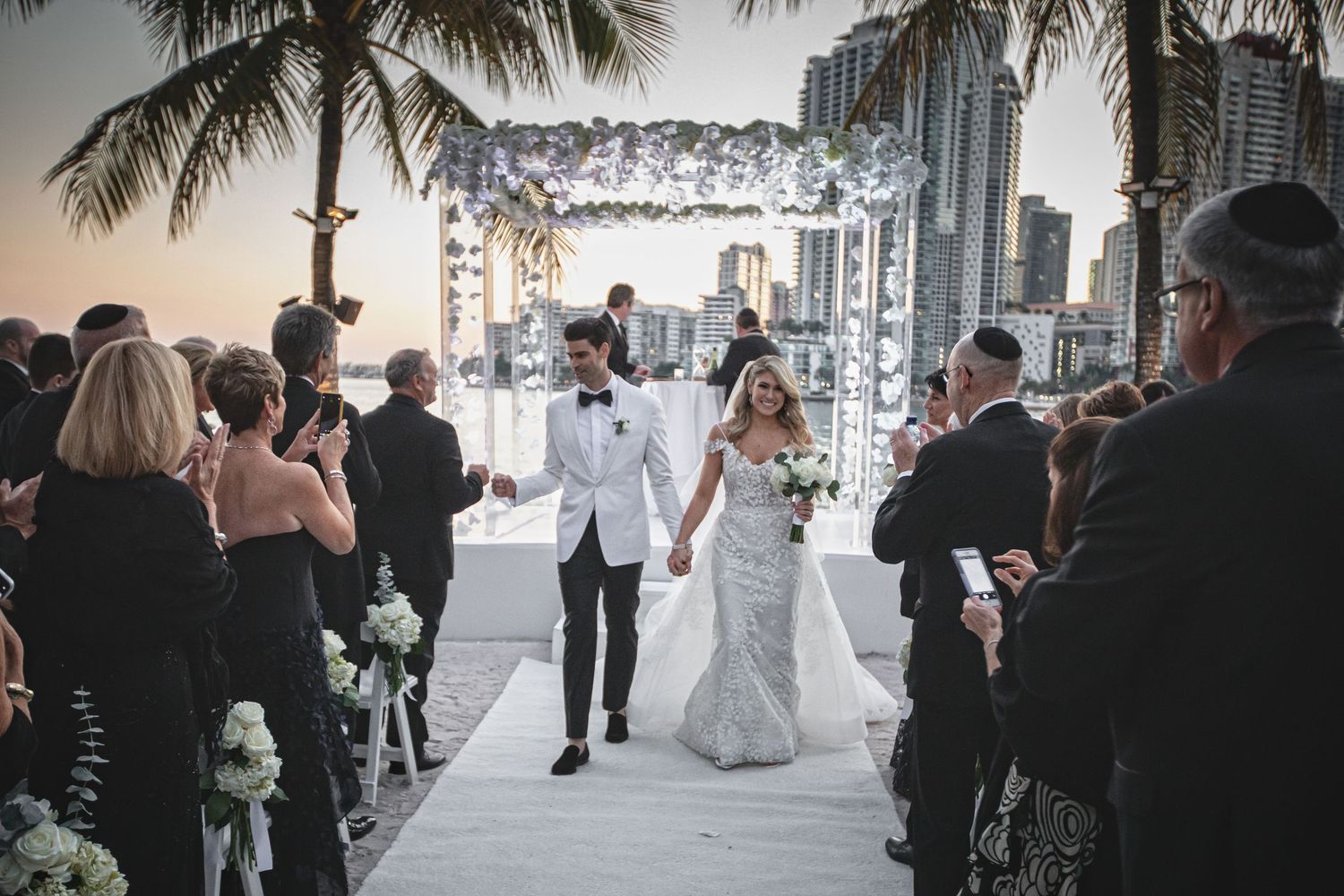 Wedding ceremony setup with palm trees and ocean view from luxury venue.