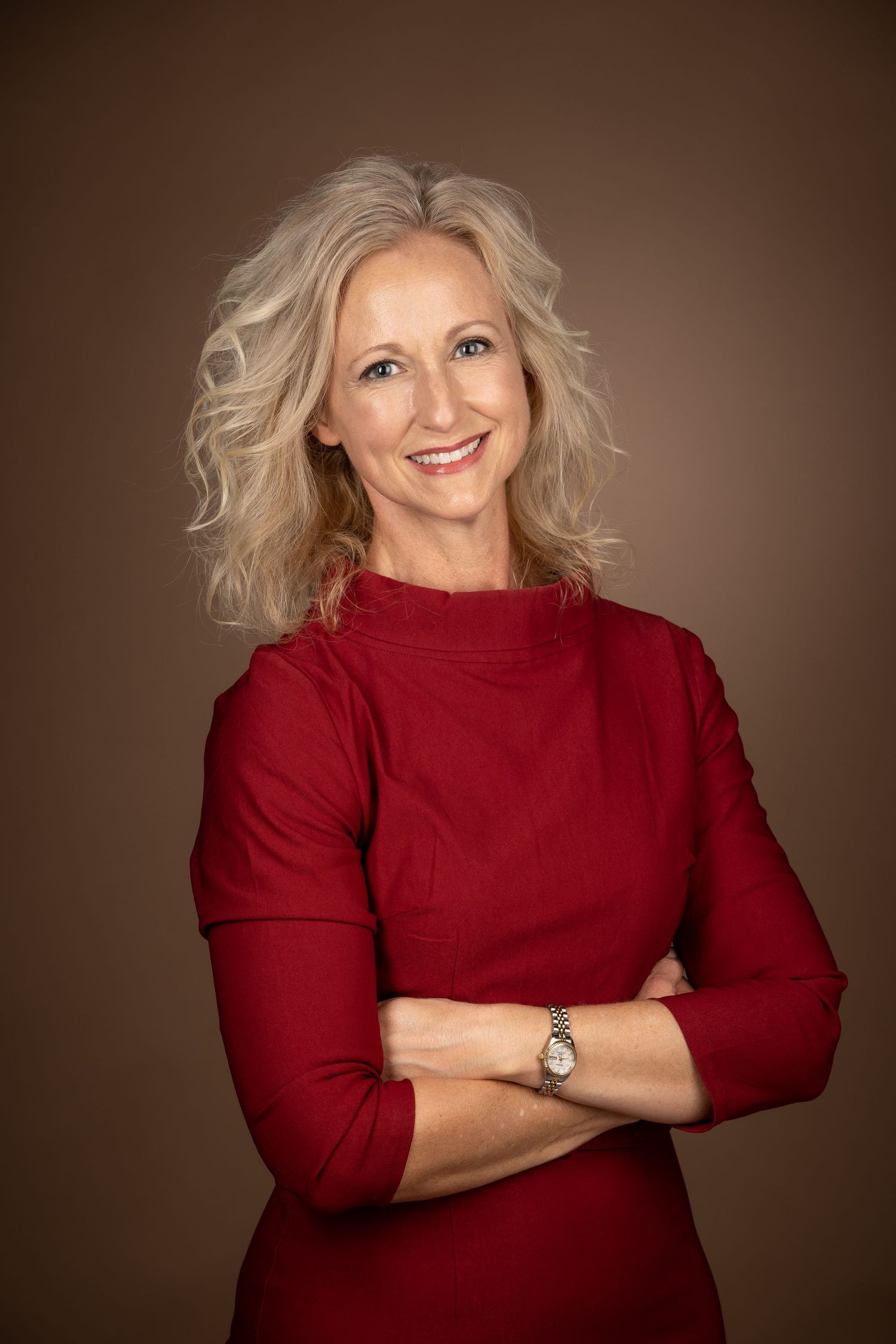 Woman wearing a red sweater strikes different poses against a brown studio backdrop while smiling warmly.