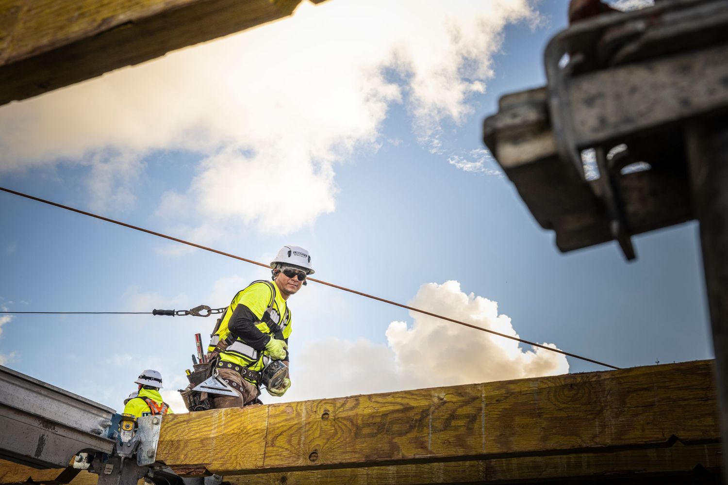 Construction workers in safety gear install wooden roof trusses on a residential building project.