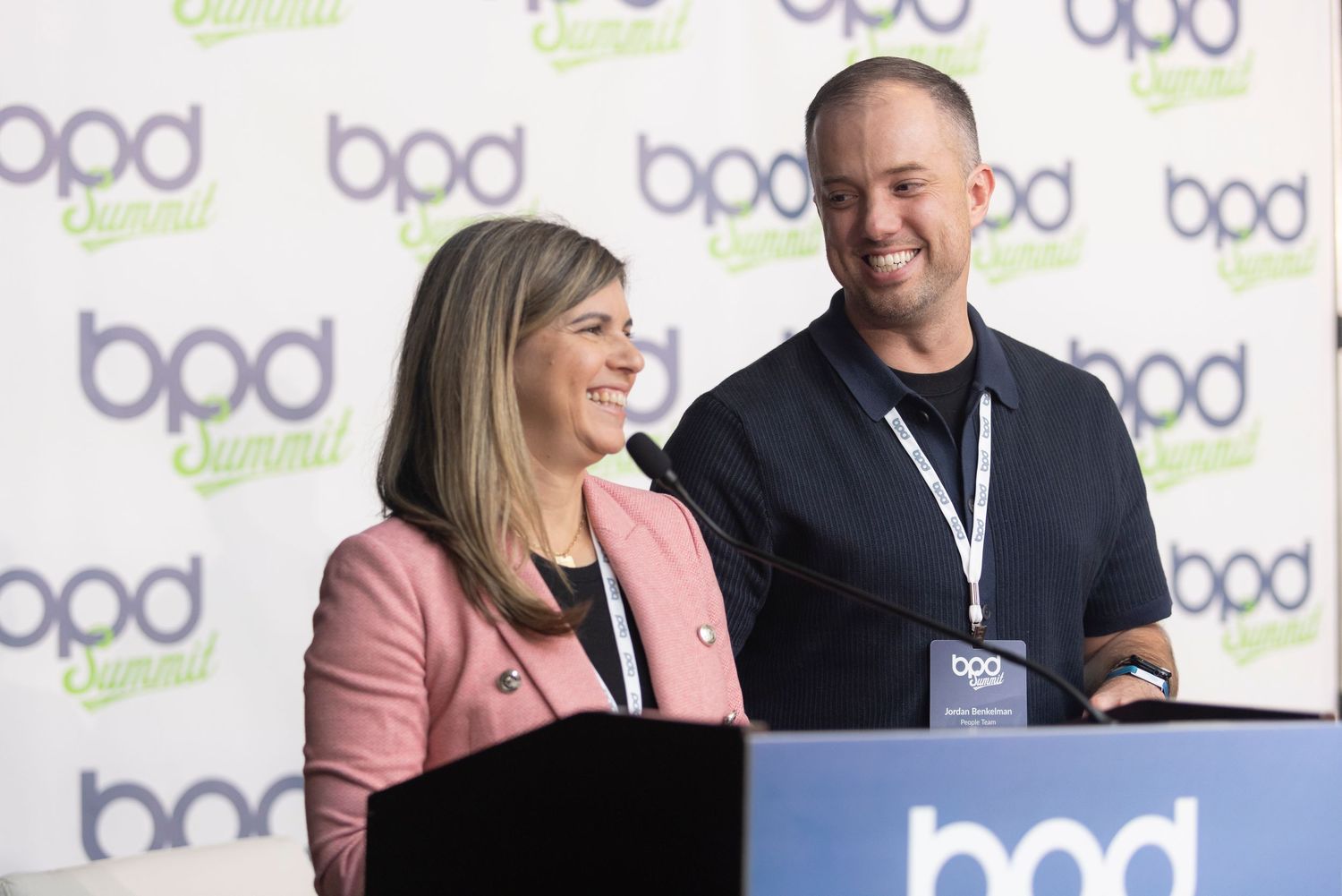 Corporate event attendees networking and sharing a laugh together at a professional conference with BPD branding.
