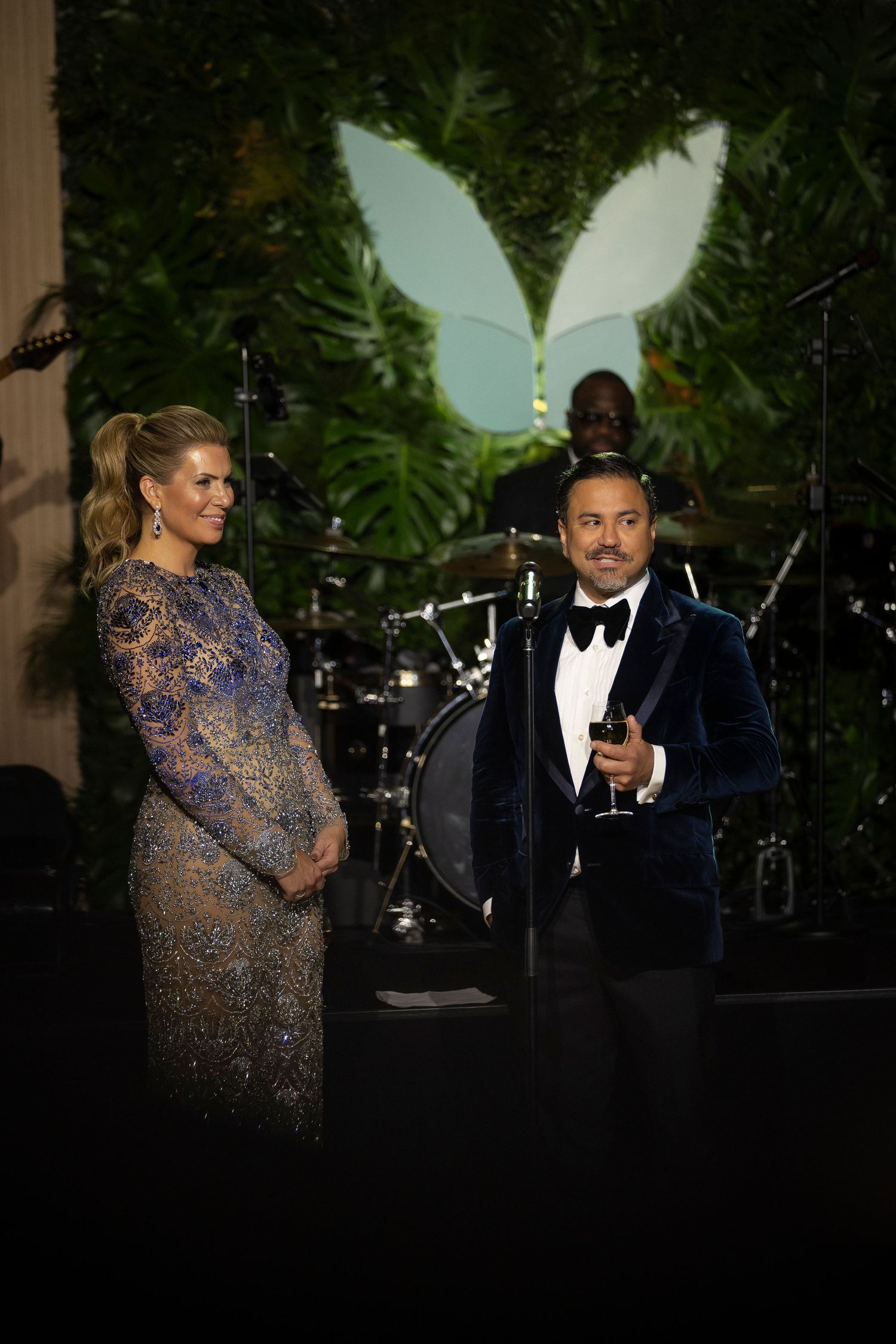Two performers entertain guests at an elegant evening event with live music and tropical decor.