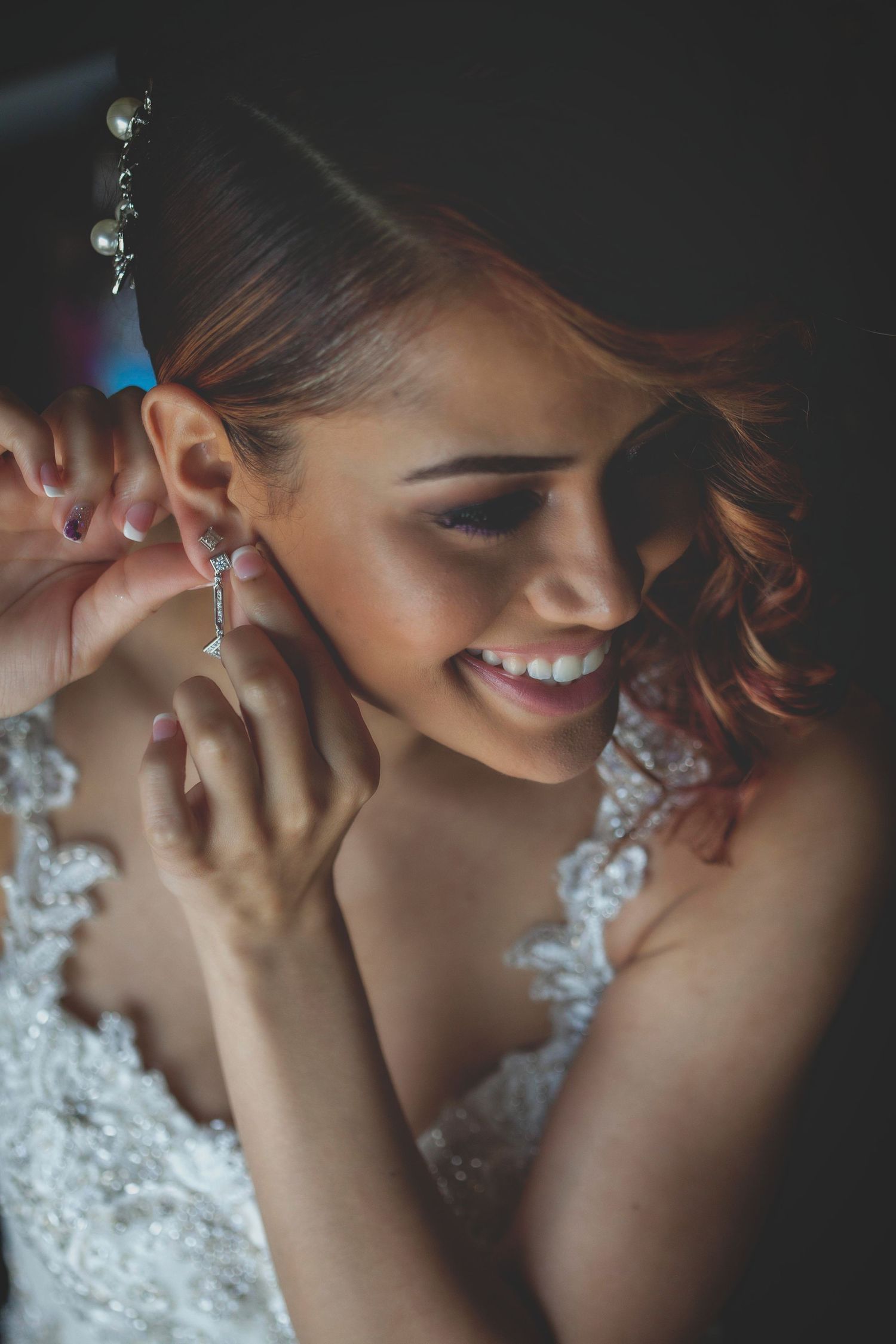 Close-up of bride putting on elegant crystal earrings.