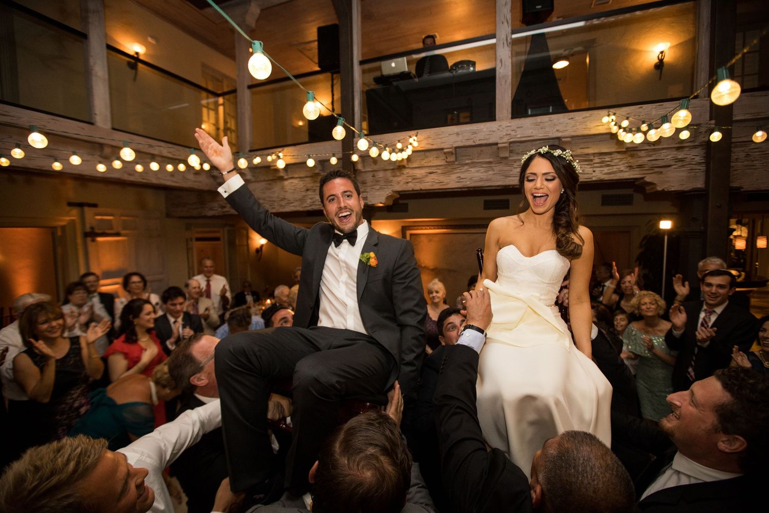 Wedding reception celebration with string lights and dancing guests.