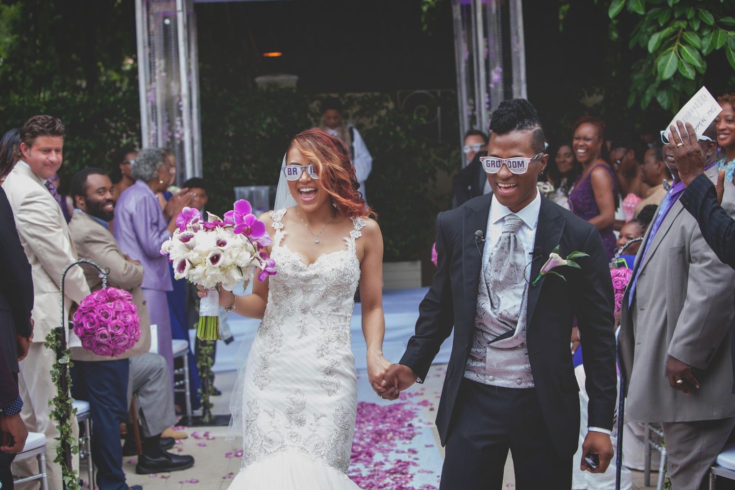 Wedding party celebrates on an elegant outdoor deck decorated with pink floral arrangements.