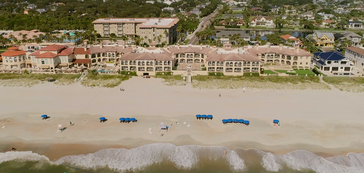 Panoramic aerial shot of luxury beachfront condominiums and resorts along the coastline.