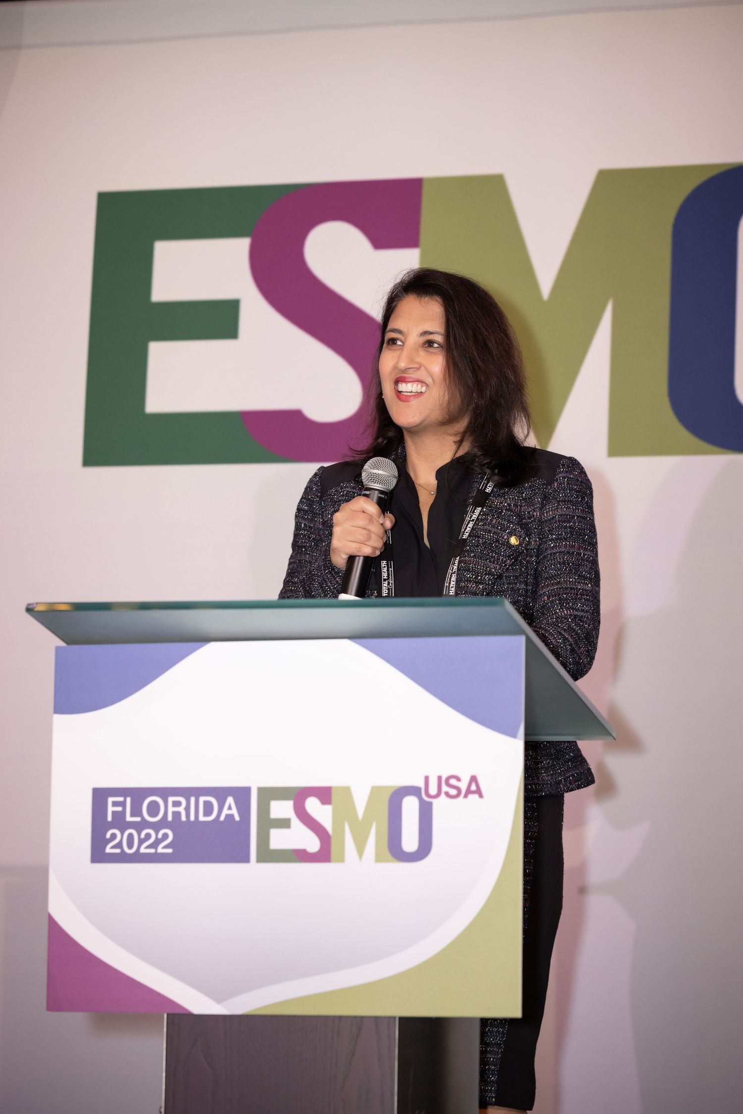 Speaker presenting at the 2022 Florida SMU USA conference in front of purple and green signage.