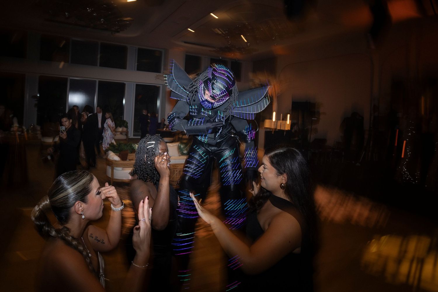 People dance and celebrate at a nighttime event with lighting effects and a festive atmosphere.
