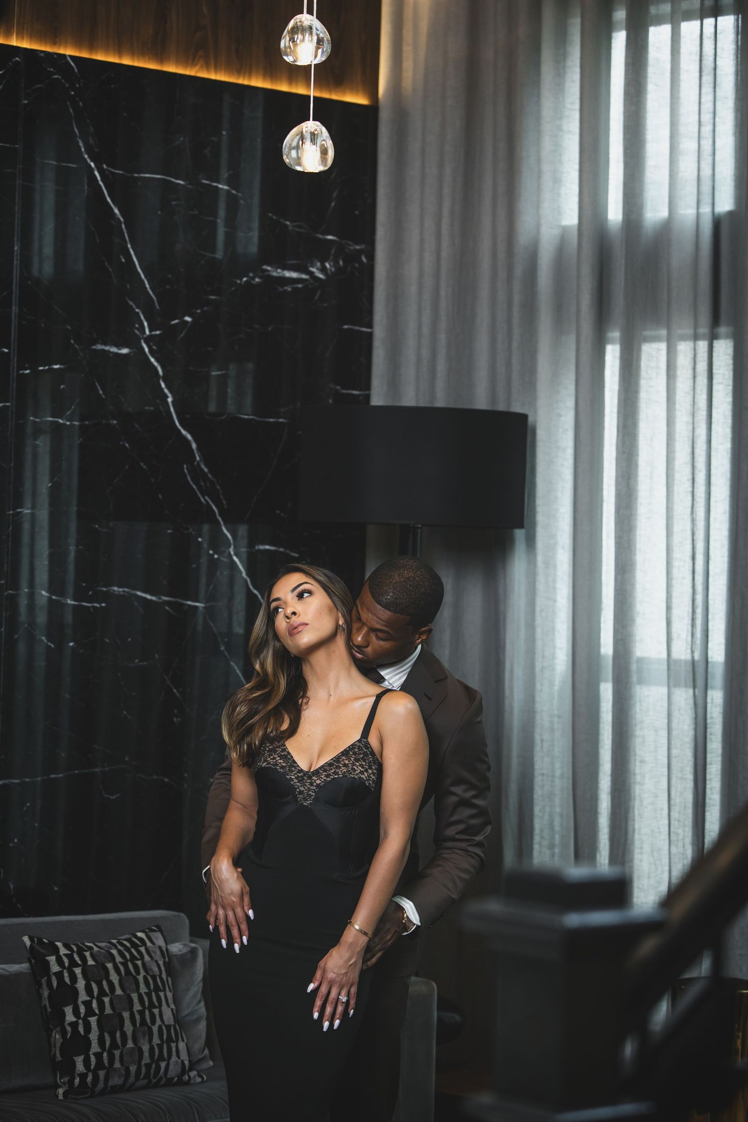 Romantic couple photoshoot in luxurious room with dramatic lighting and marble walls.