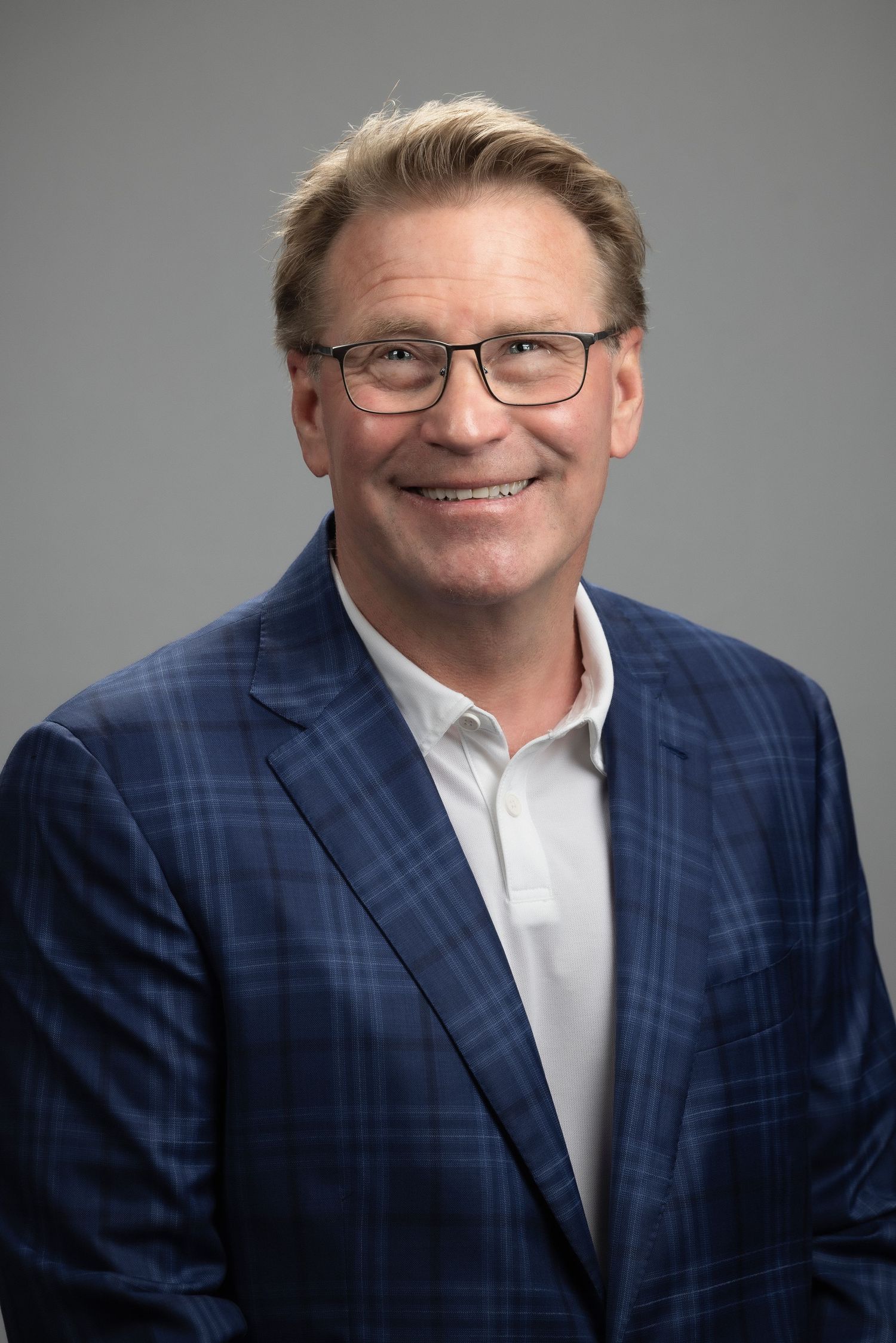 Professional headshots of someone wearing a navy plaid suit jacket and white shirt against a gray background.