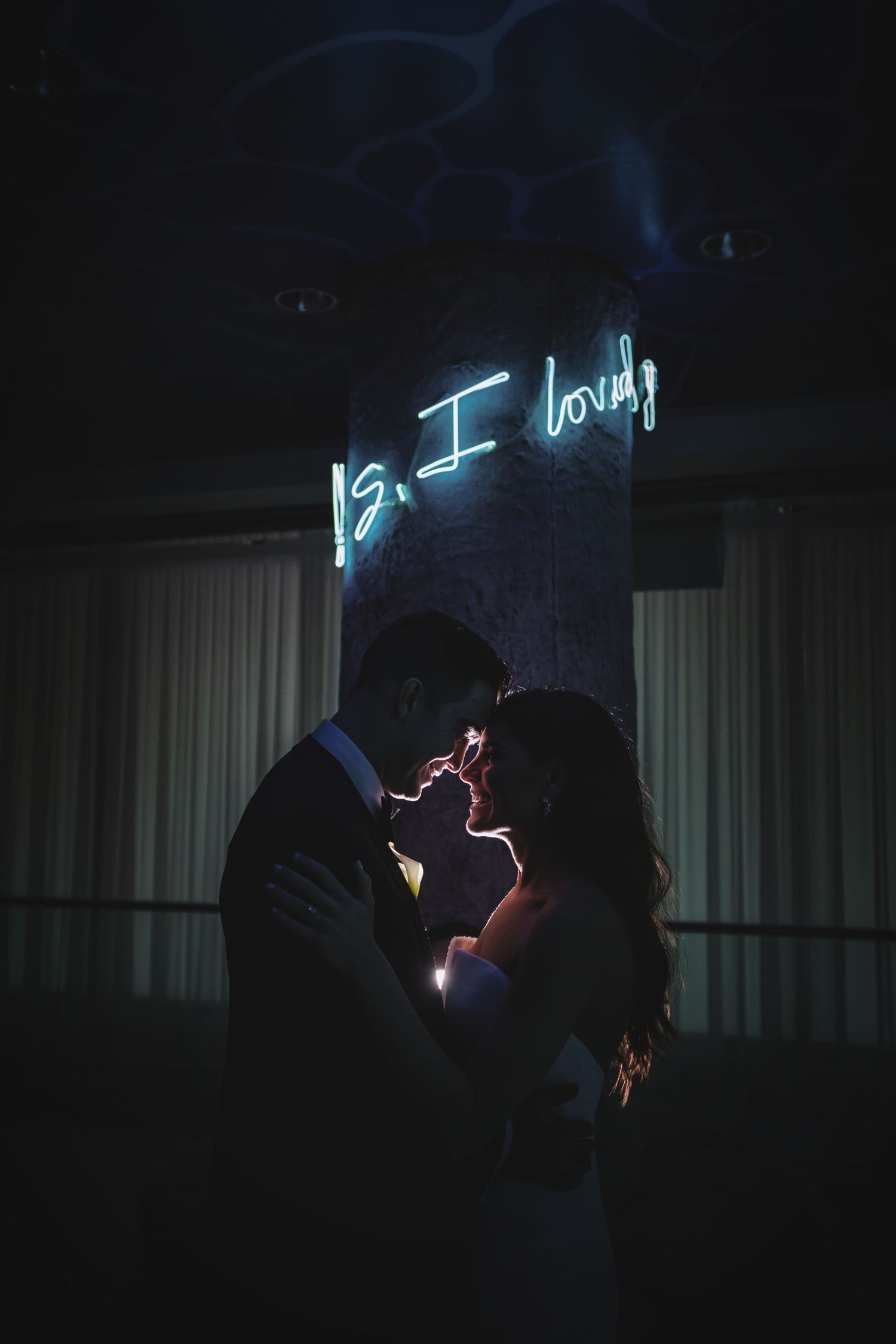 Silhouetted figures dancing in a dark room with blue neon lights.