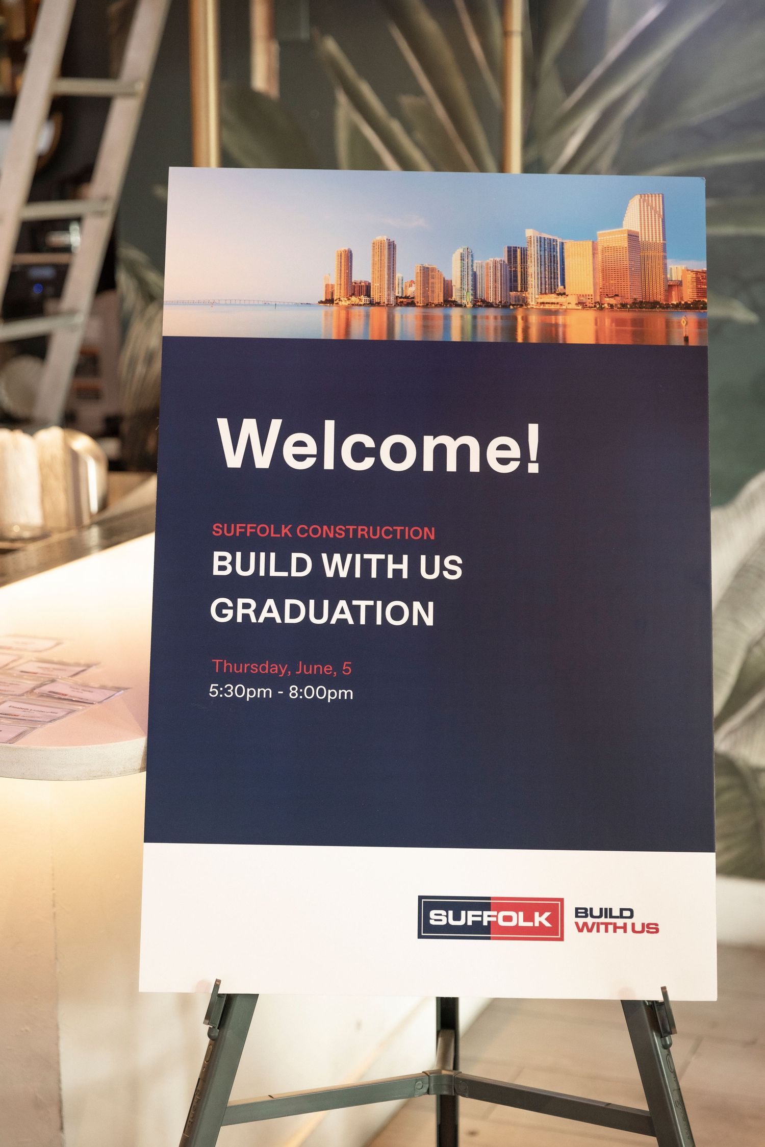 A set of welcome signs and graduation displays with Suffolk Construction branding in a corporate event setting.