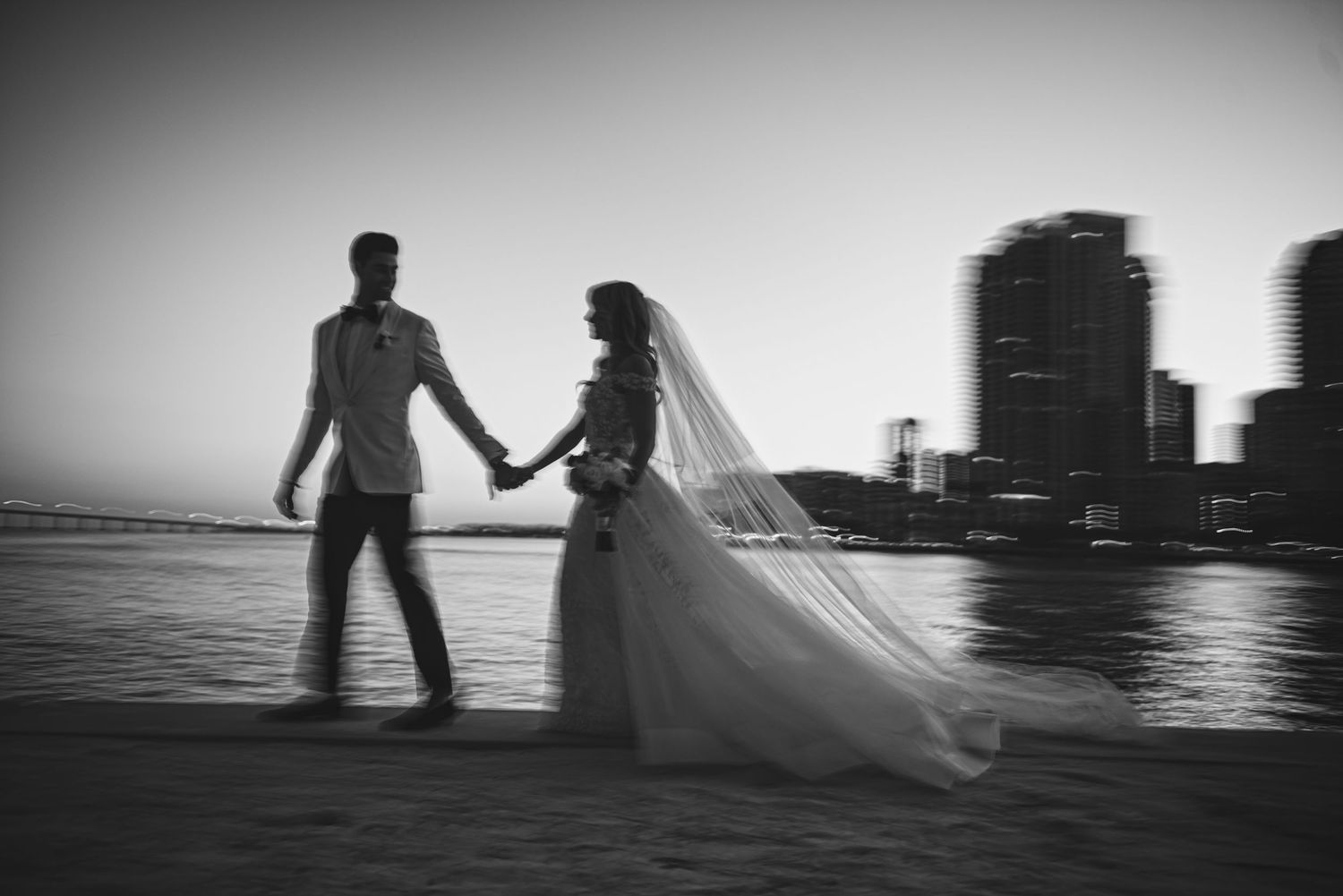 Silhouetted couple holding hands at sunset with a cityscape backdrop.