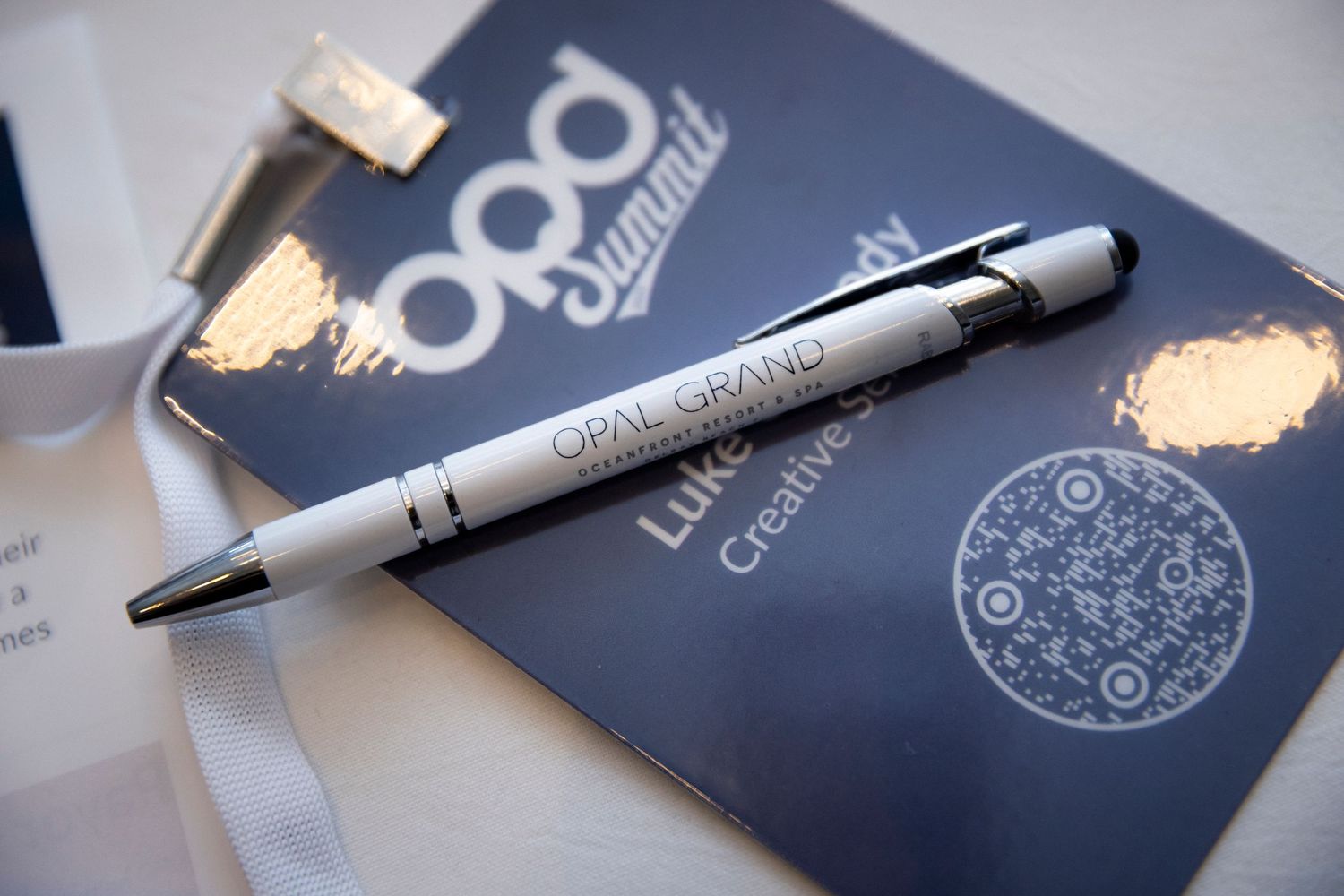 Blue branded business cards and pens arranged on reflective surface.