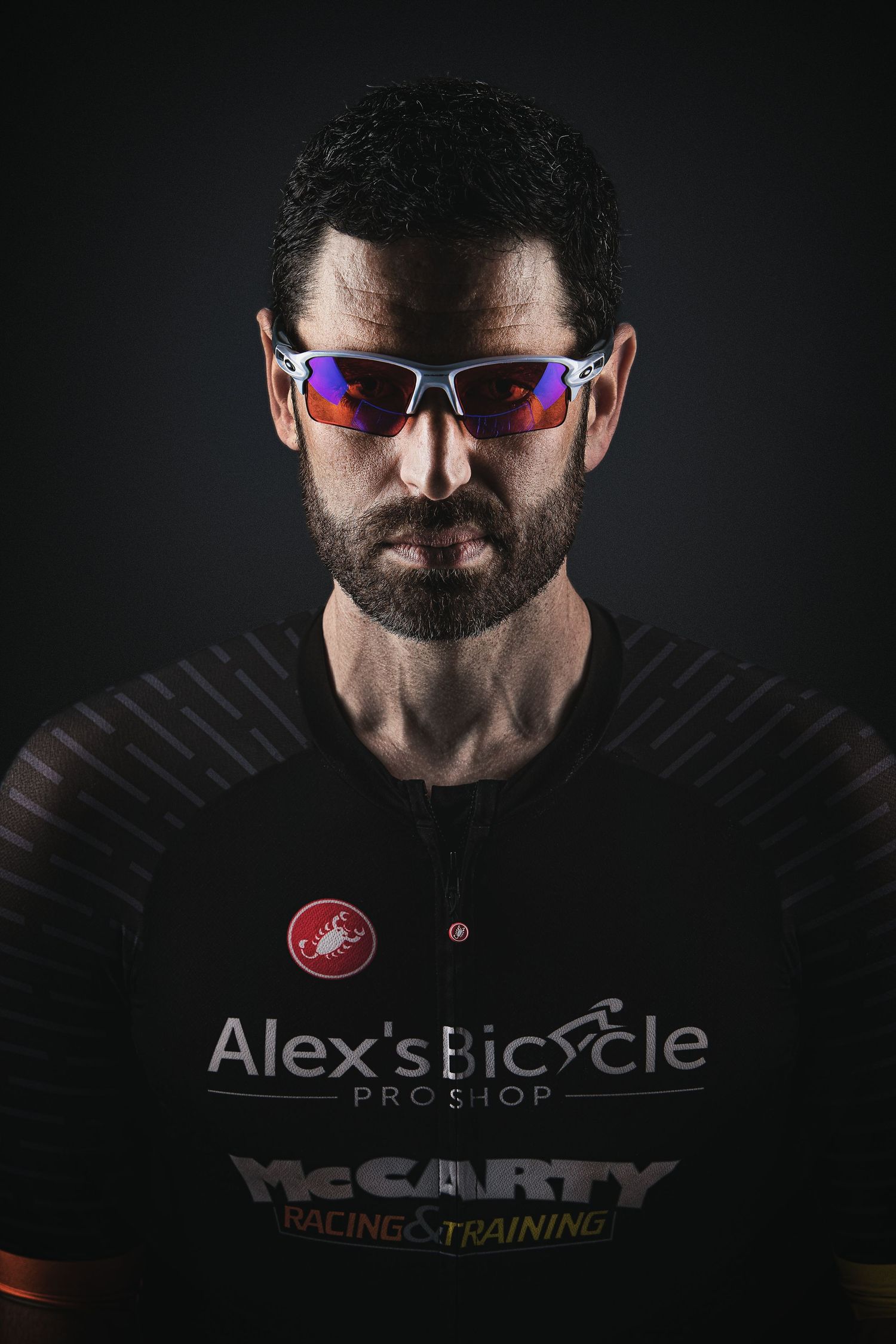 Dark dramatic portrait showcasing sports eyewear and casual streetwear with a dramatic black background.