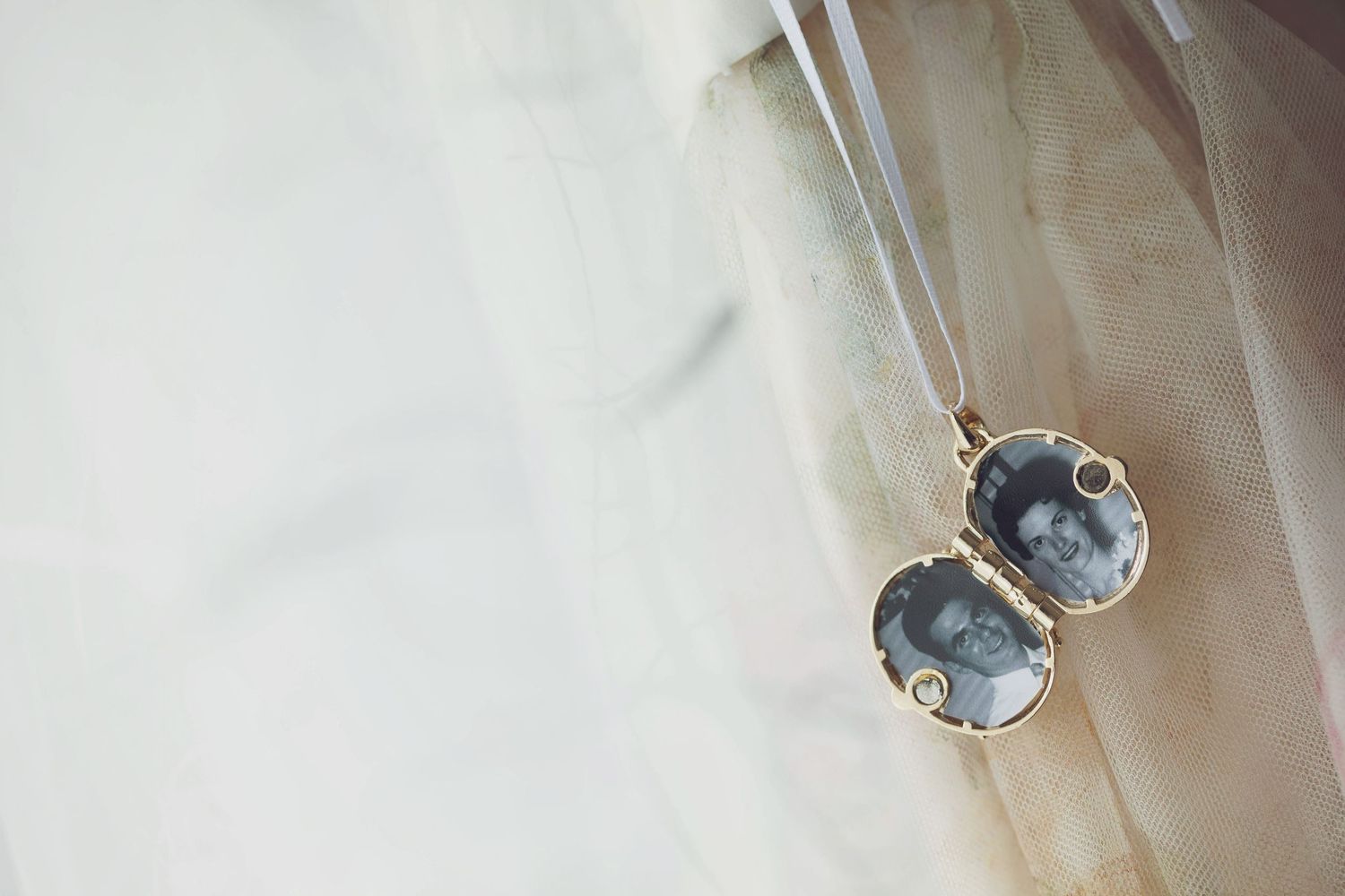Close-up of delicate earrings with pearl details on light fabric.