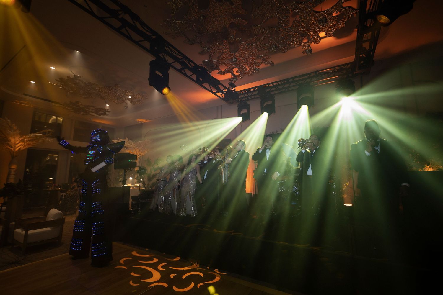 Green laser beams illuminate a dark performance venue with stage lighting equipment and atmospheric effects.