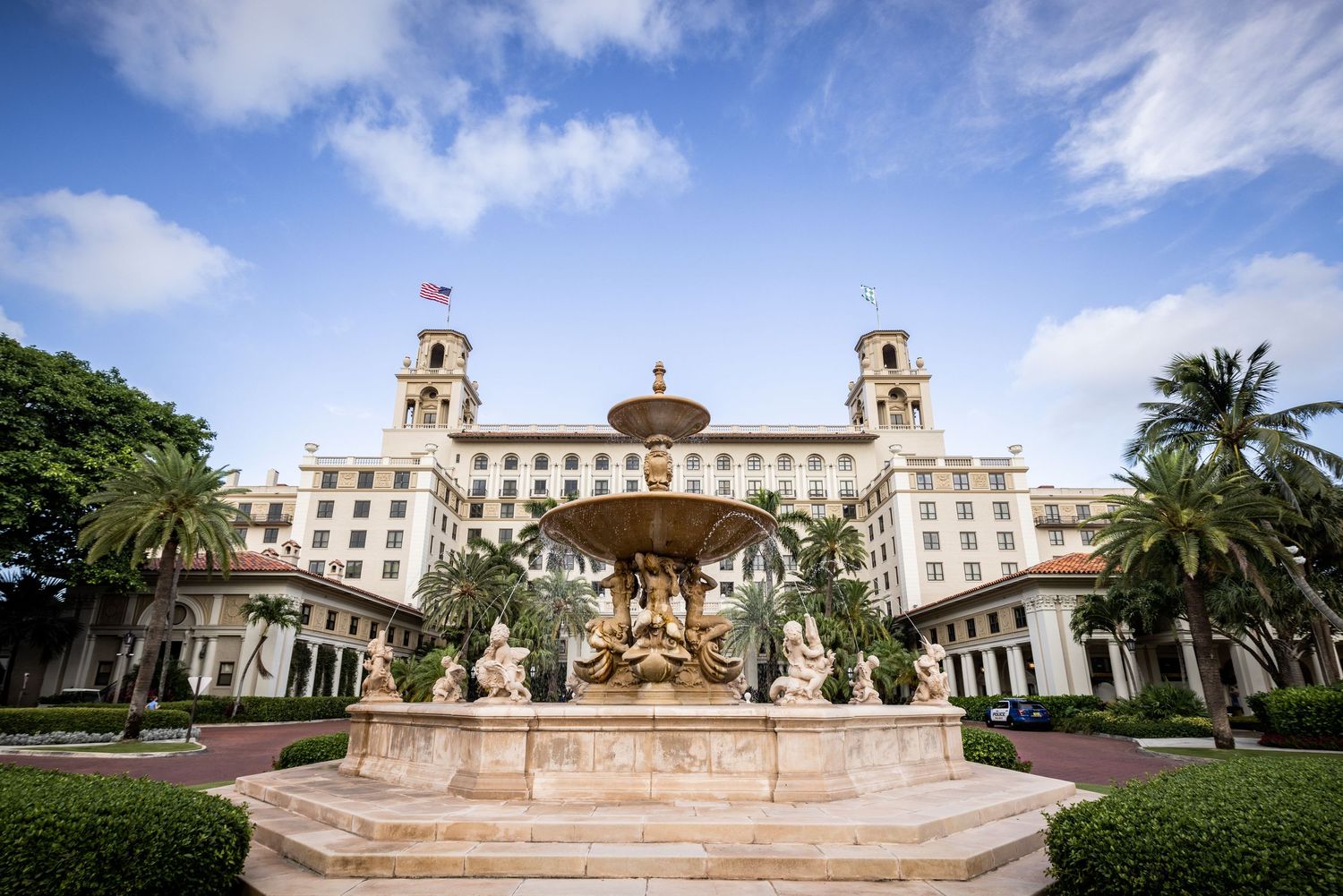 Panoramic view of a grand Mediterranean-style resort building with palm trees and ornate architecture.