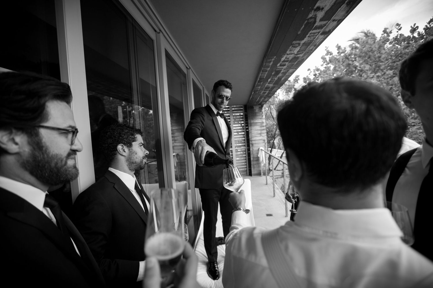 Wedding party walks along covered walkway in formal attire.