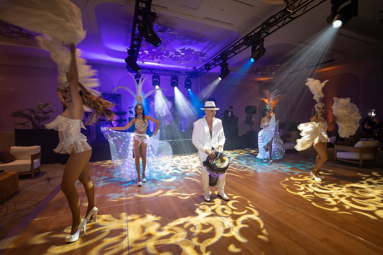 Dancers perform on a dimly lit dance floor illuminated by mesmerizing purple and yellow lighting patterns.