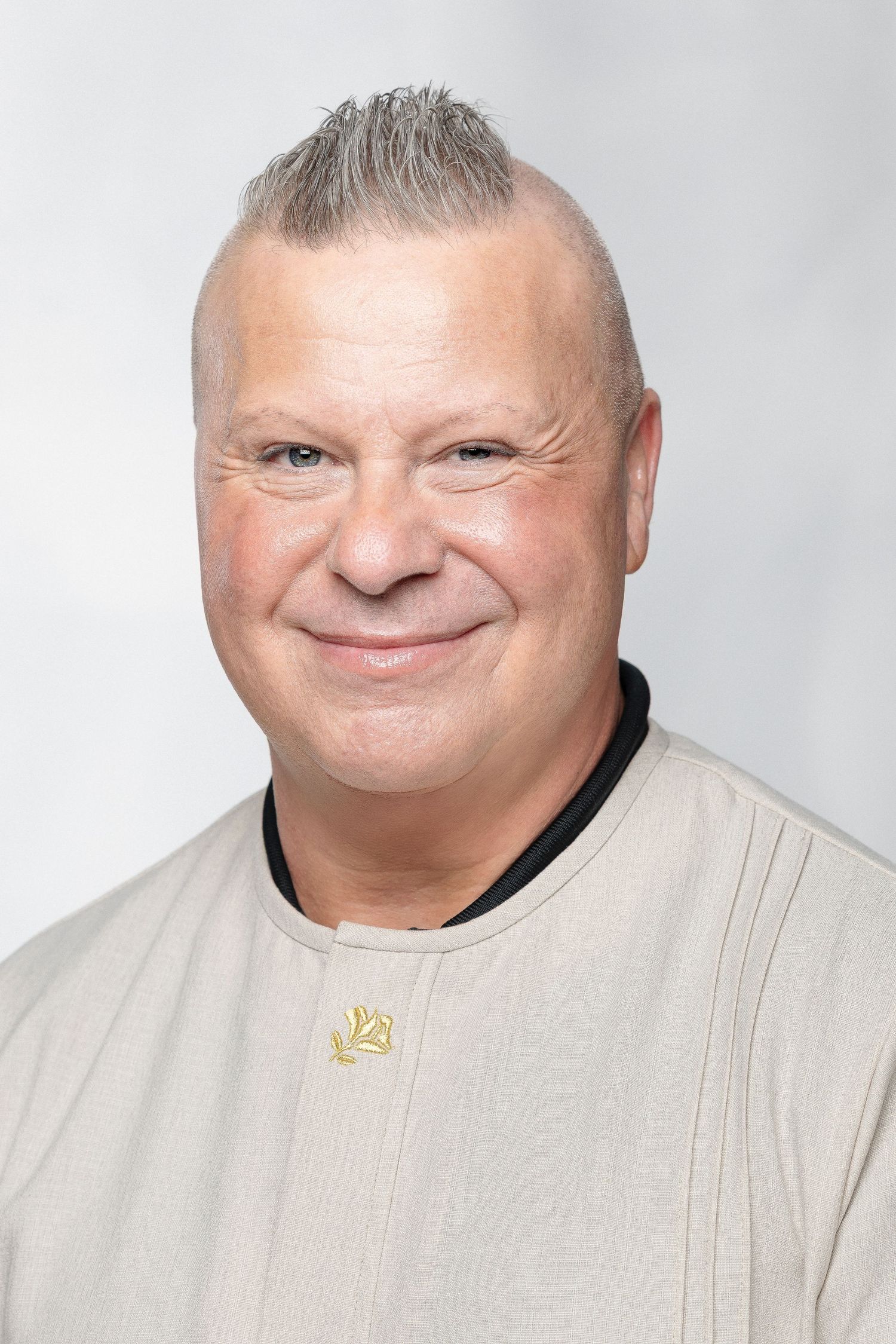 A person wearing a light-colored top smiles warmly against a bright white background.
