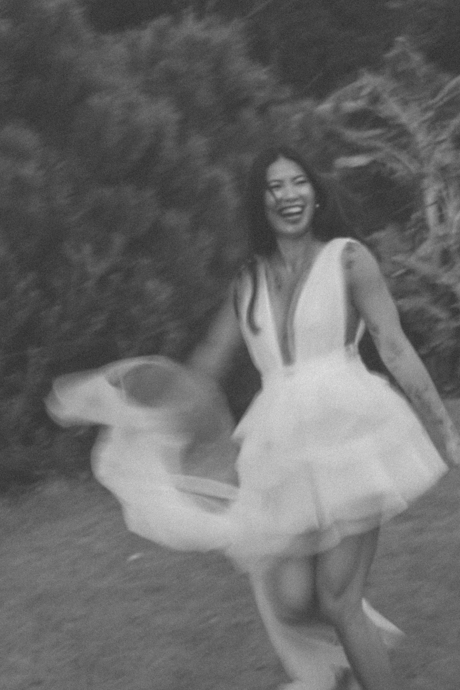 Blurred motion capture of someone spinning in white dress against dark background.