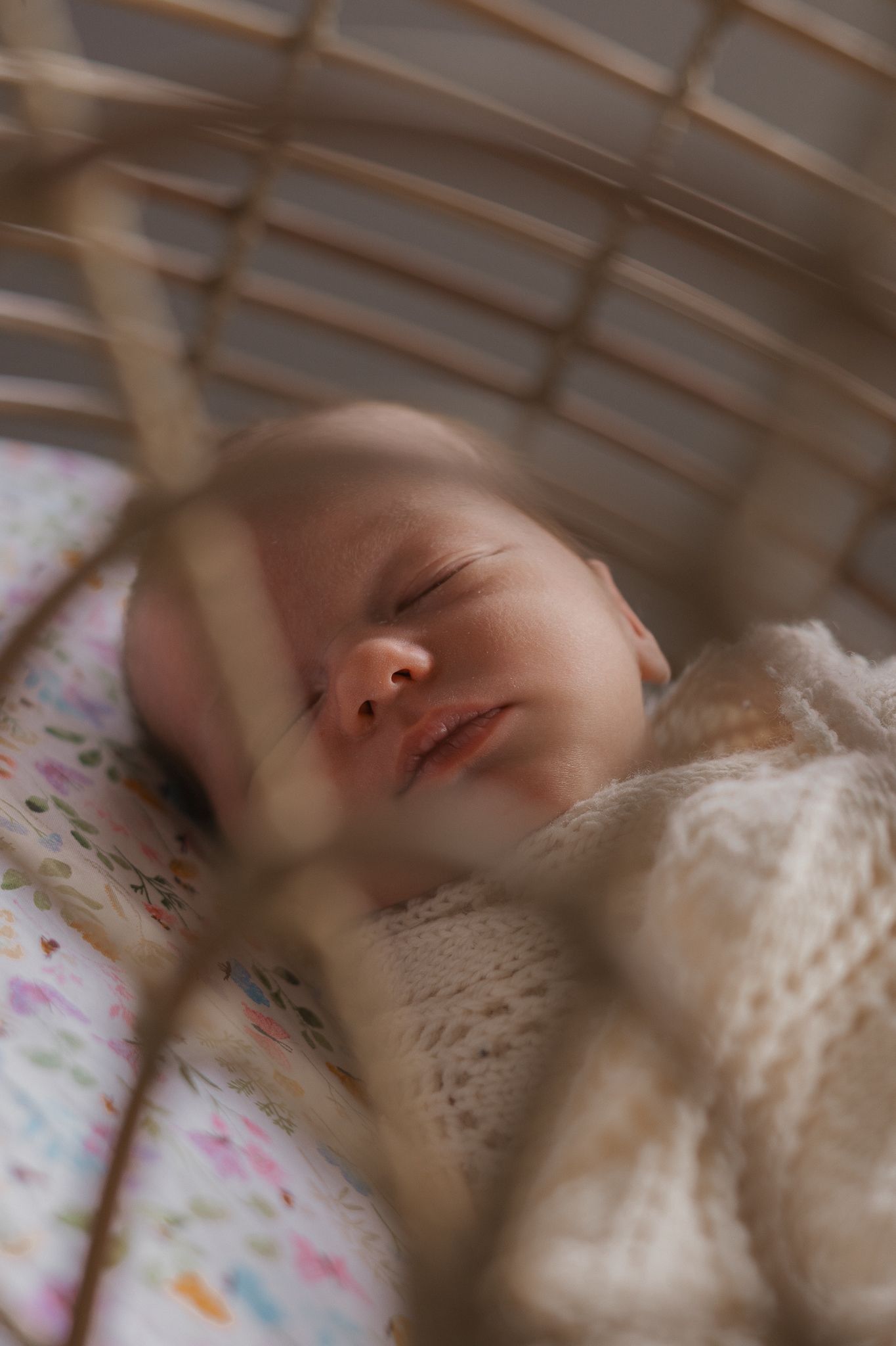 Peaceful sleeping baby in white lace clothing resting in a crib with floral patterned bedding.