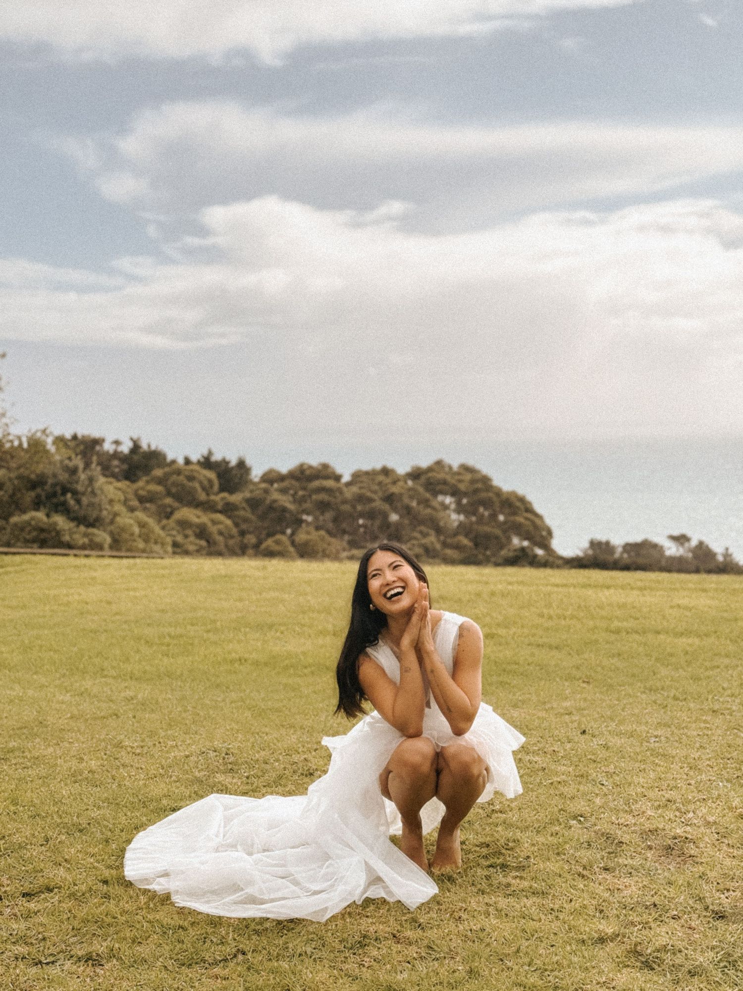 Person in flowing white dress moving gracefully across grassy hilltop.