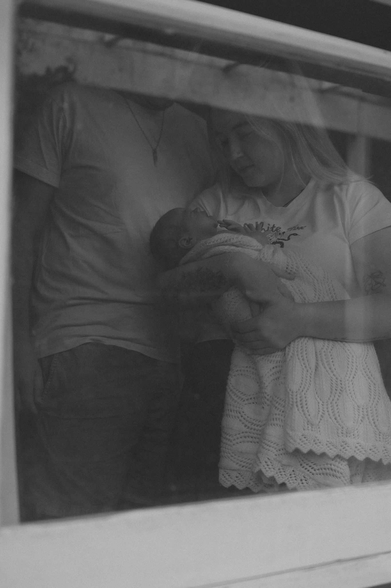 Black and white panoramic series capturing tender moments of a newborn resting on white blankets.